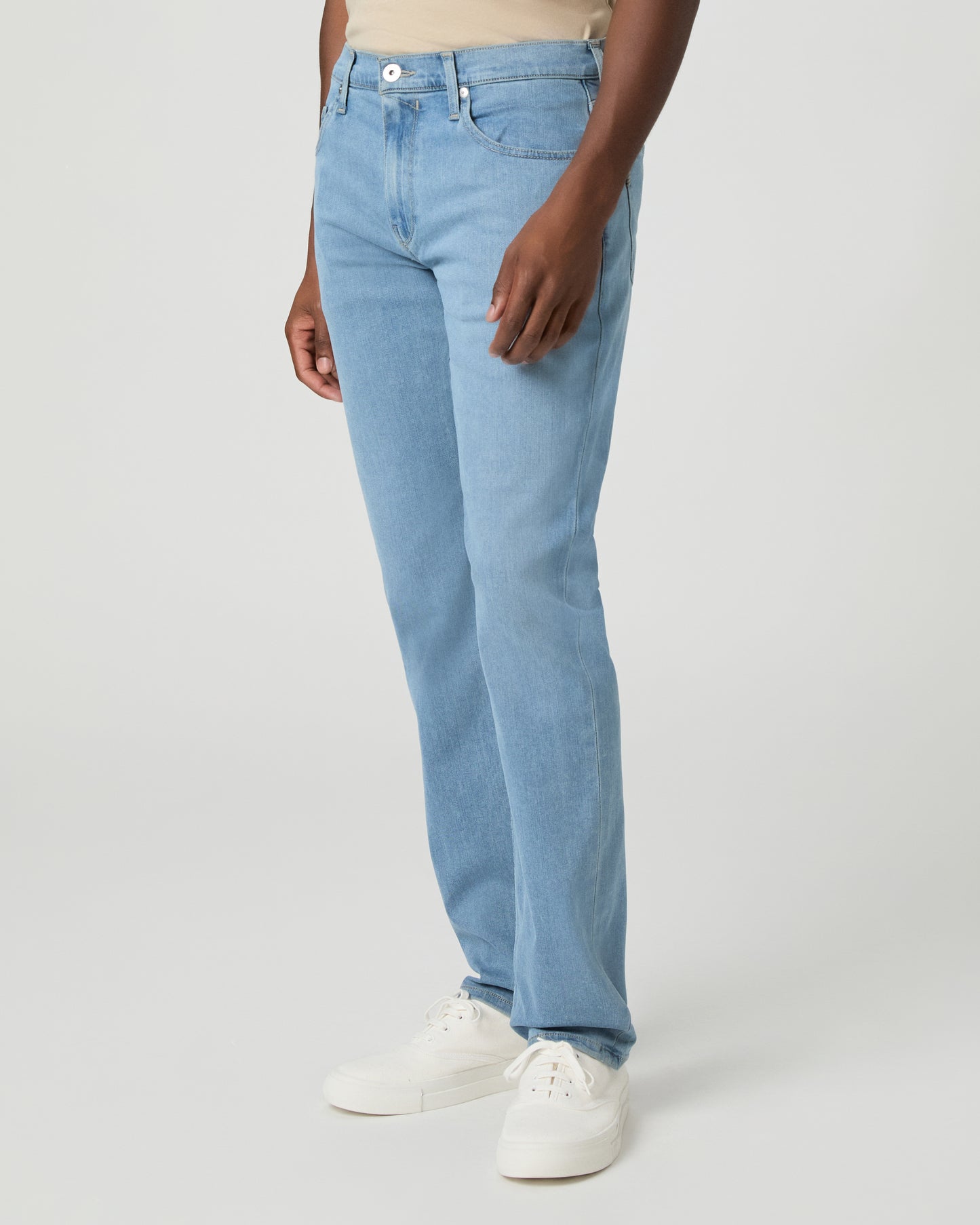 Man wearing a beige t-shirt, light blue jeans on a white background