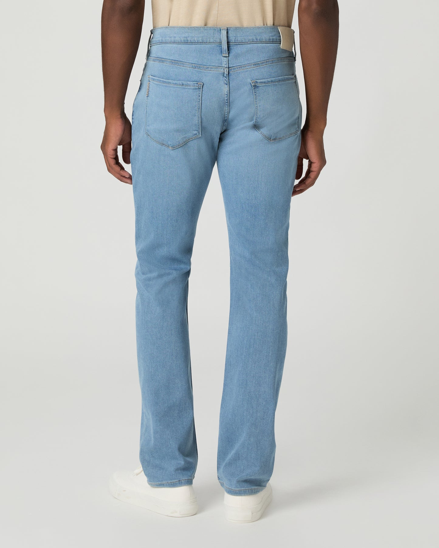 Man wearing a beige t-shirt, light blue jeans on a white background