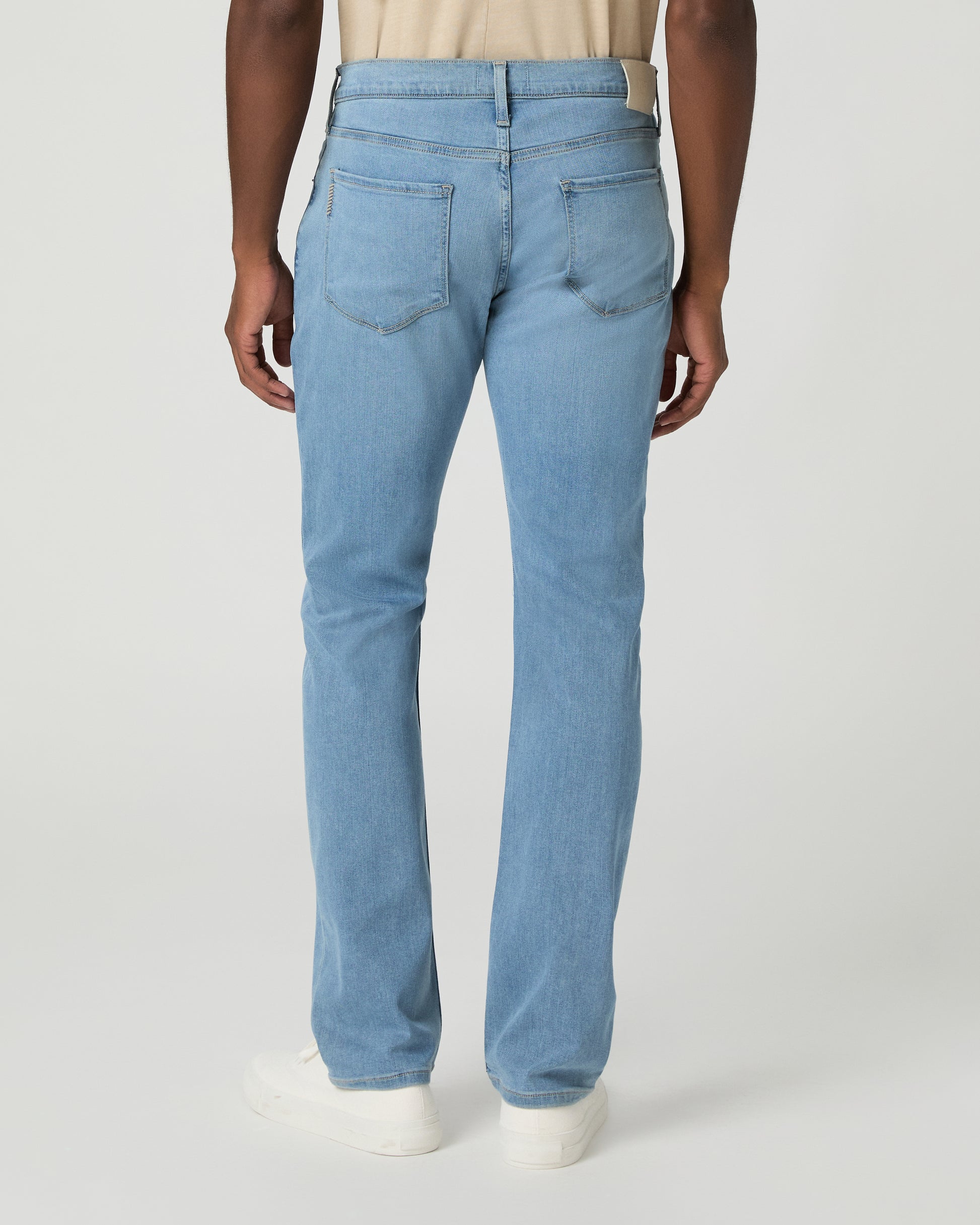 Man wearing a beige t-shirt, light blue jeans on a white background