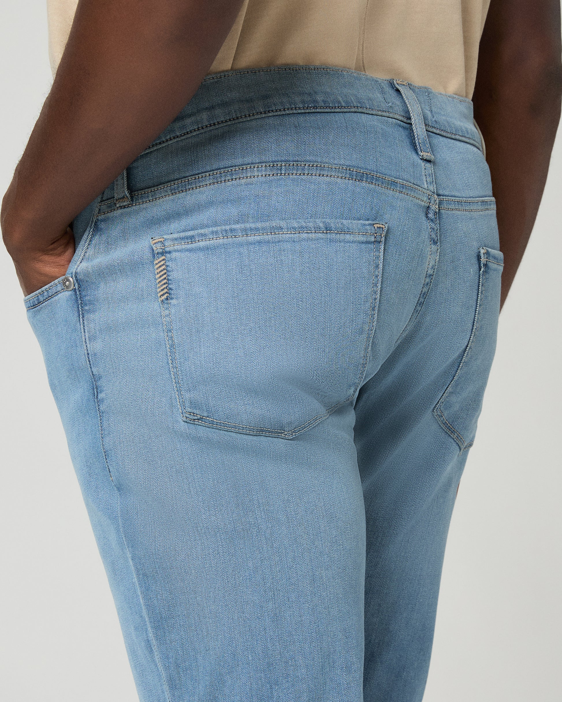 Man wearing a beige t-shirt, light blue jeans on a white background