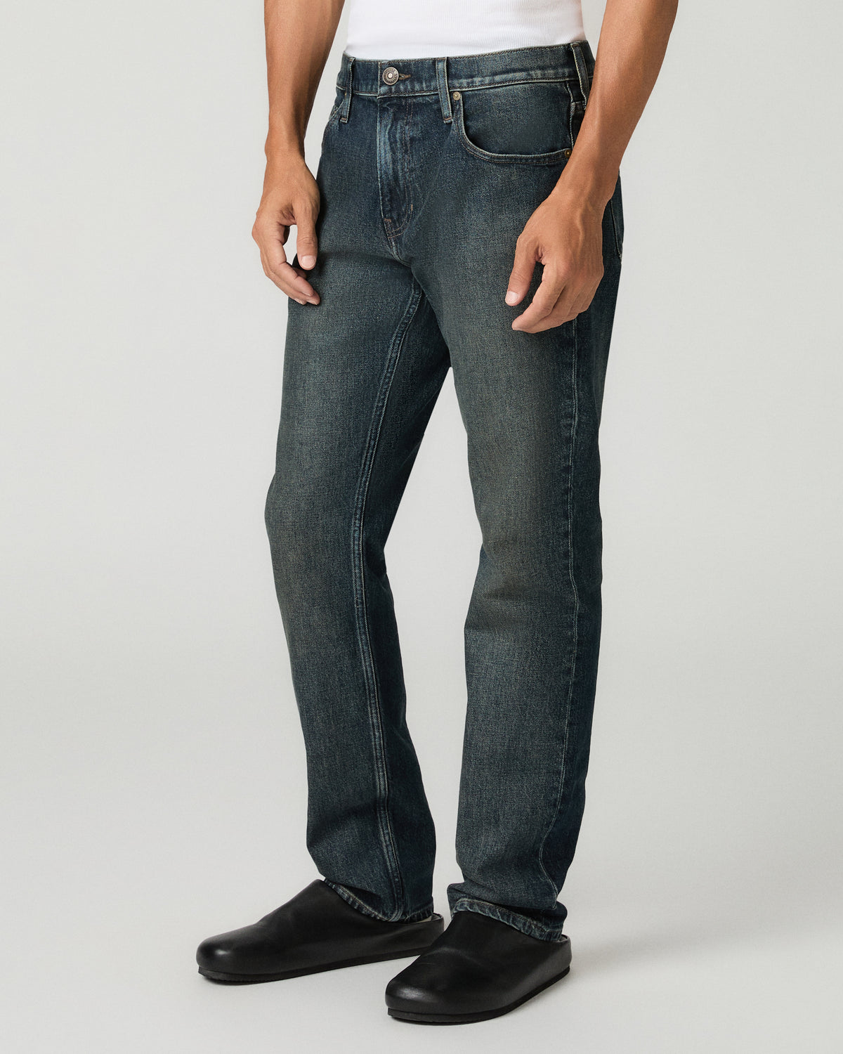 Three-quarter angle view from the waist down of a man wearing charcoal slim-straight jeans with subtle fading, paired with black leather loafers.