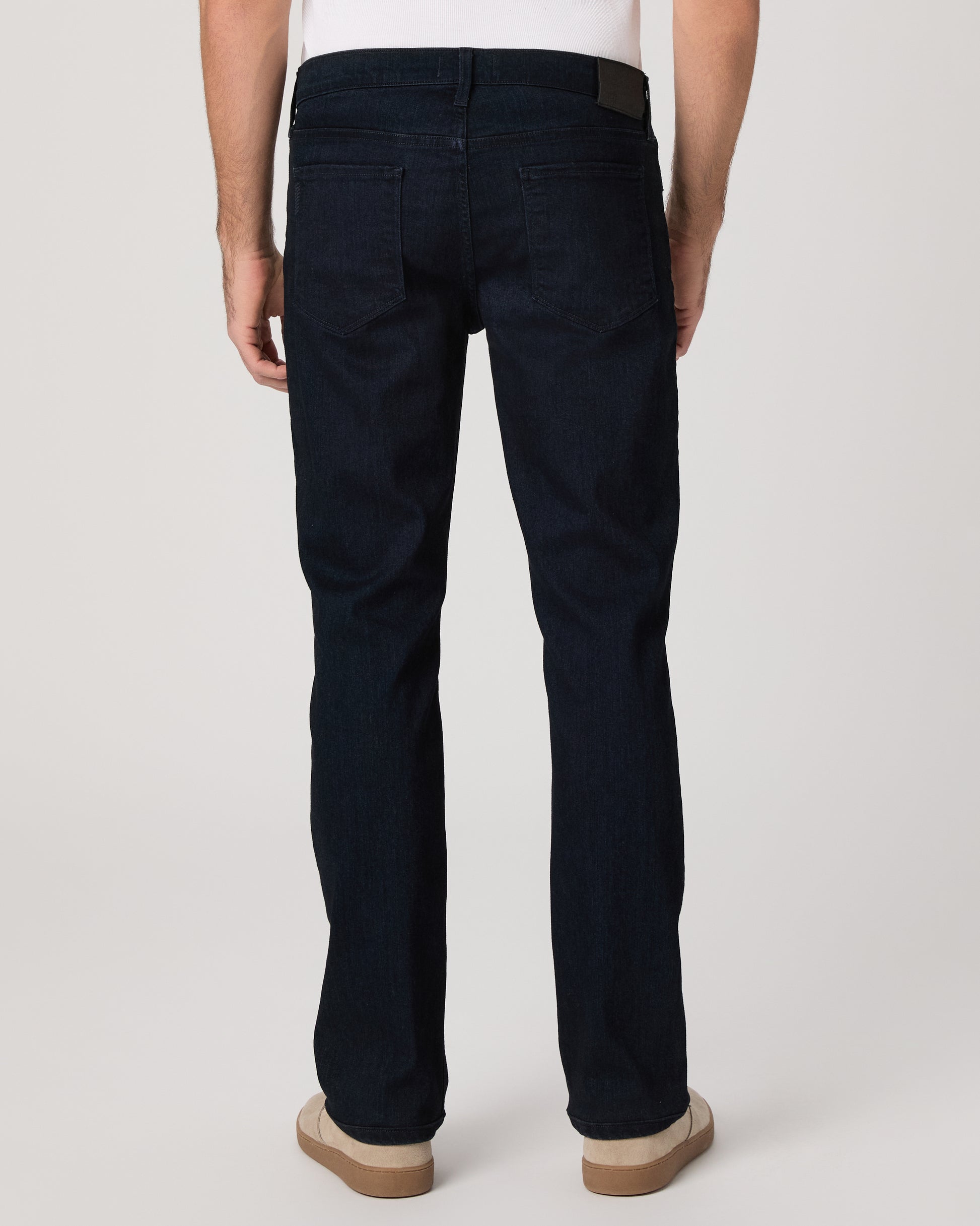 Man wearing a white tee and dark jeans on a white background