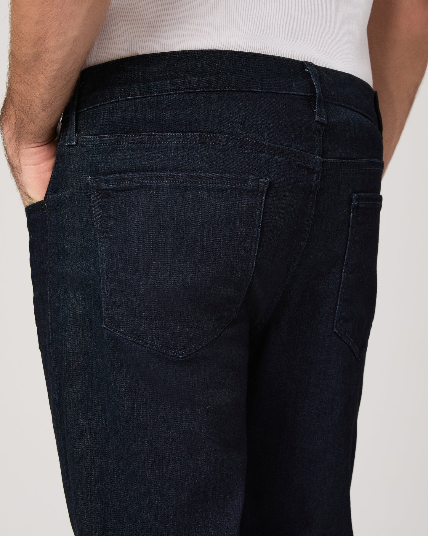 Man wearing a white tee and dark jeans on a white background