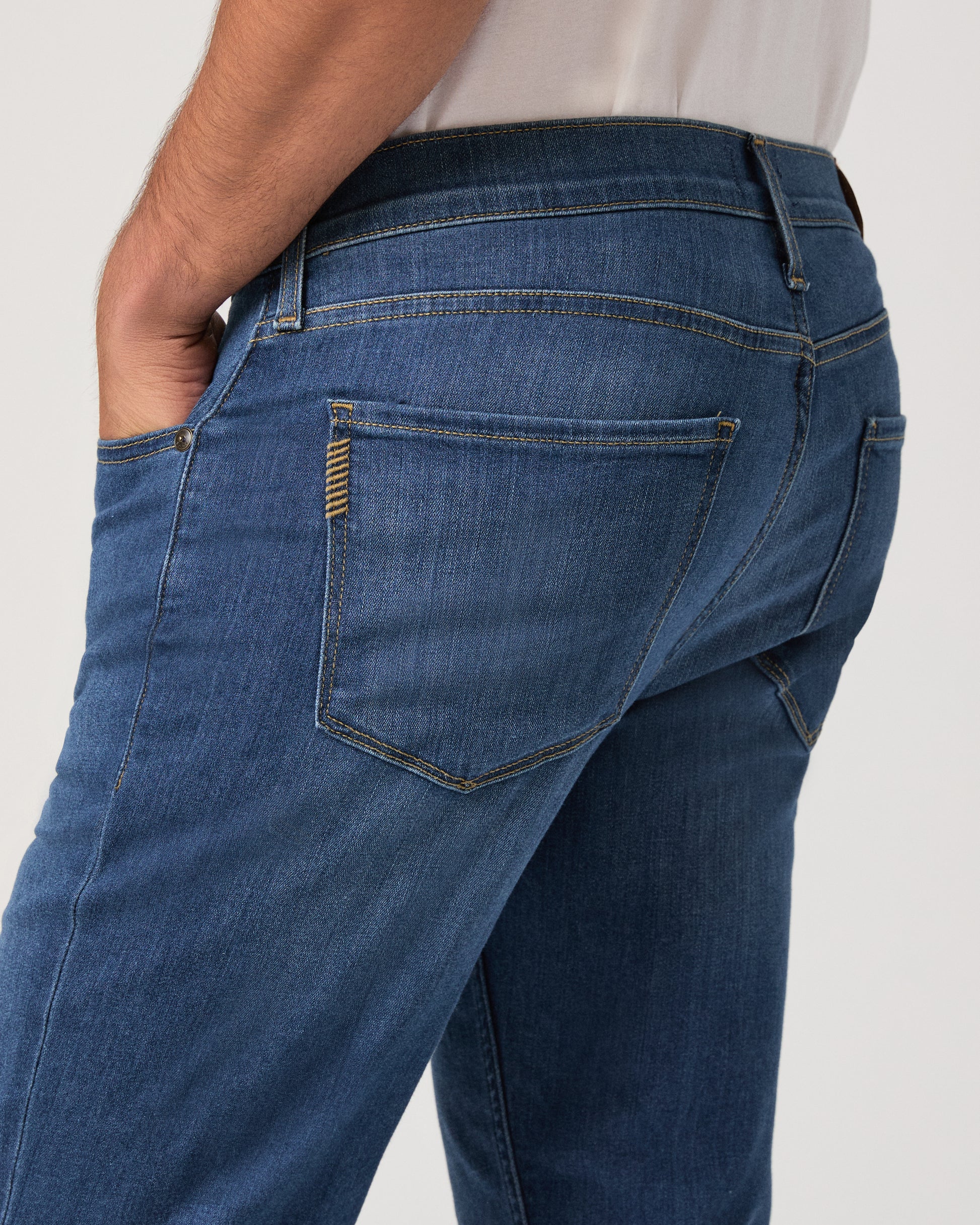 Man wearing a white shirt, blue jeans, and white shoes on a white background