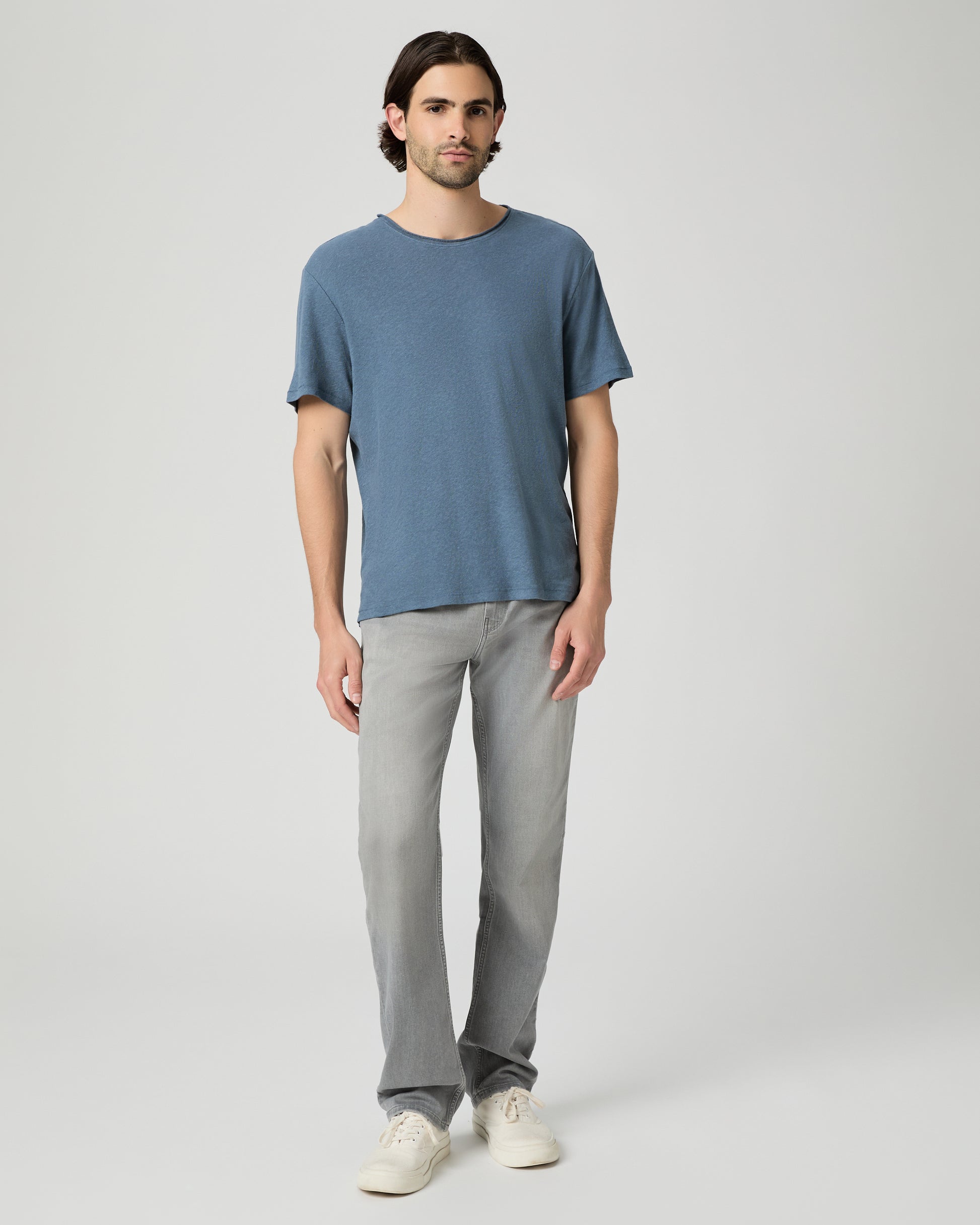 Man wearing a blue t-shirt and gray pants on a white background