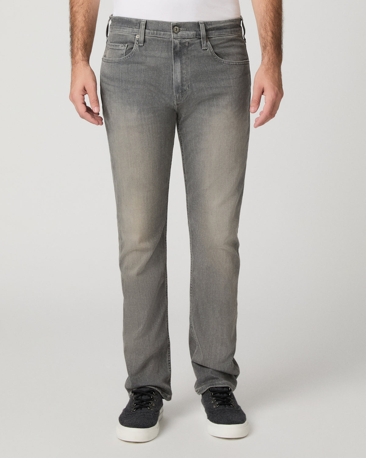 Man wearing white shirt and grey pants against a white background