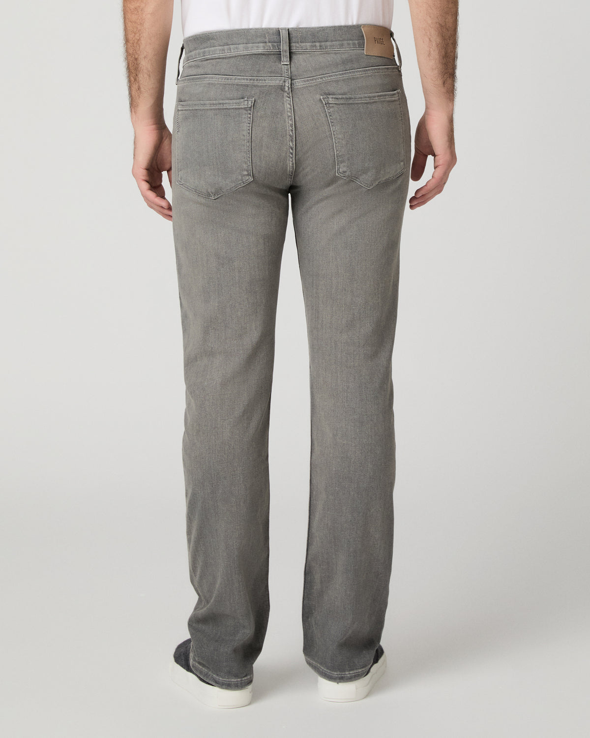 Man wearing white shirt and grey pants against a white background