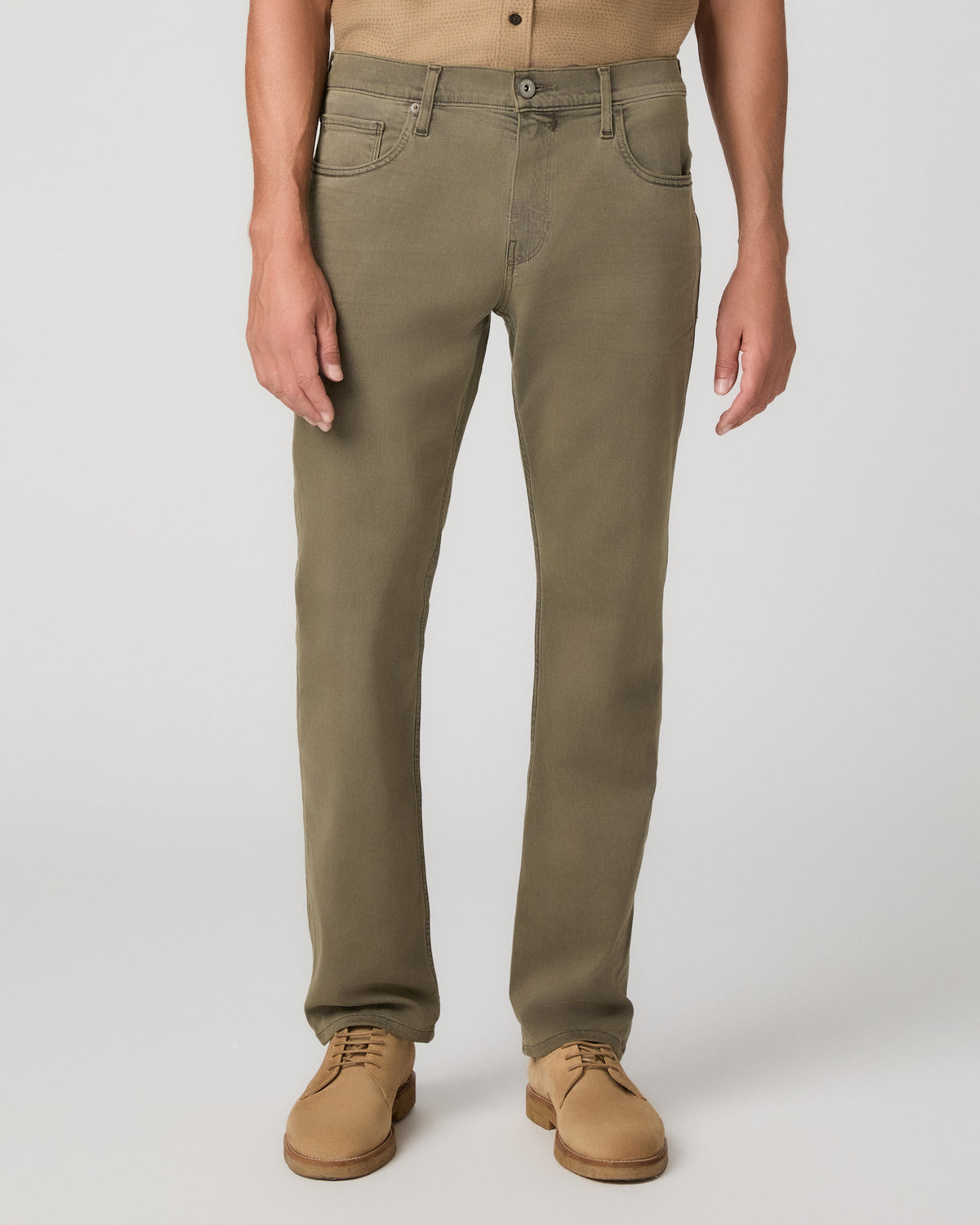 A man modeling a short-sleeve button-up shirt in tan and olive green pants, standing against a light gray studio background.