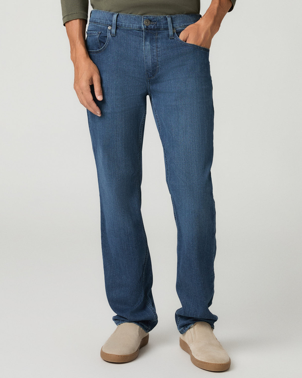 Close front view from the waist down of the medium blue wash straight jeans with fading through the thighs, hands tucked in the front pockets, paired with tan suede boots.