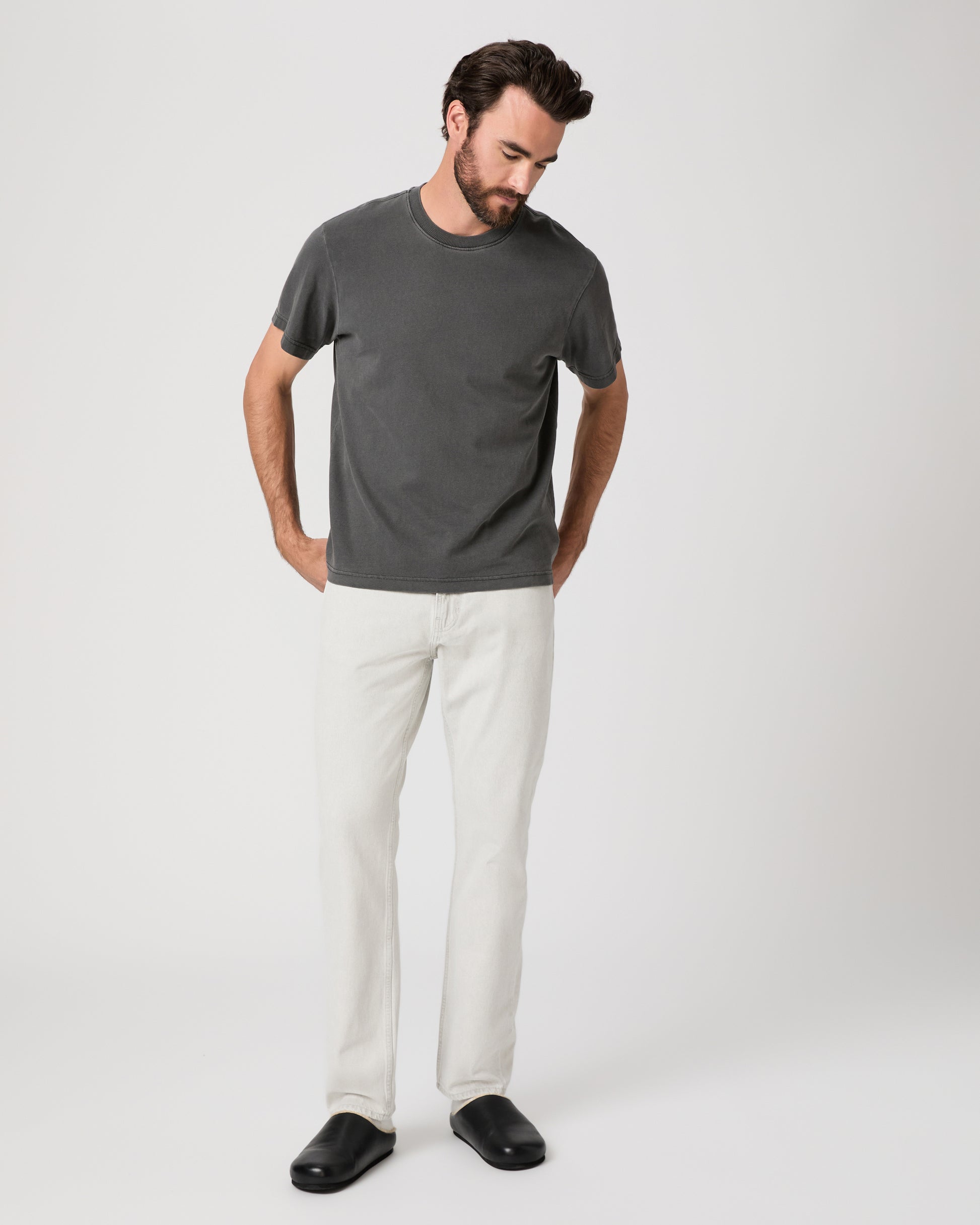 Man wearing a gray t-shirt and white pants on a white background
