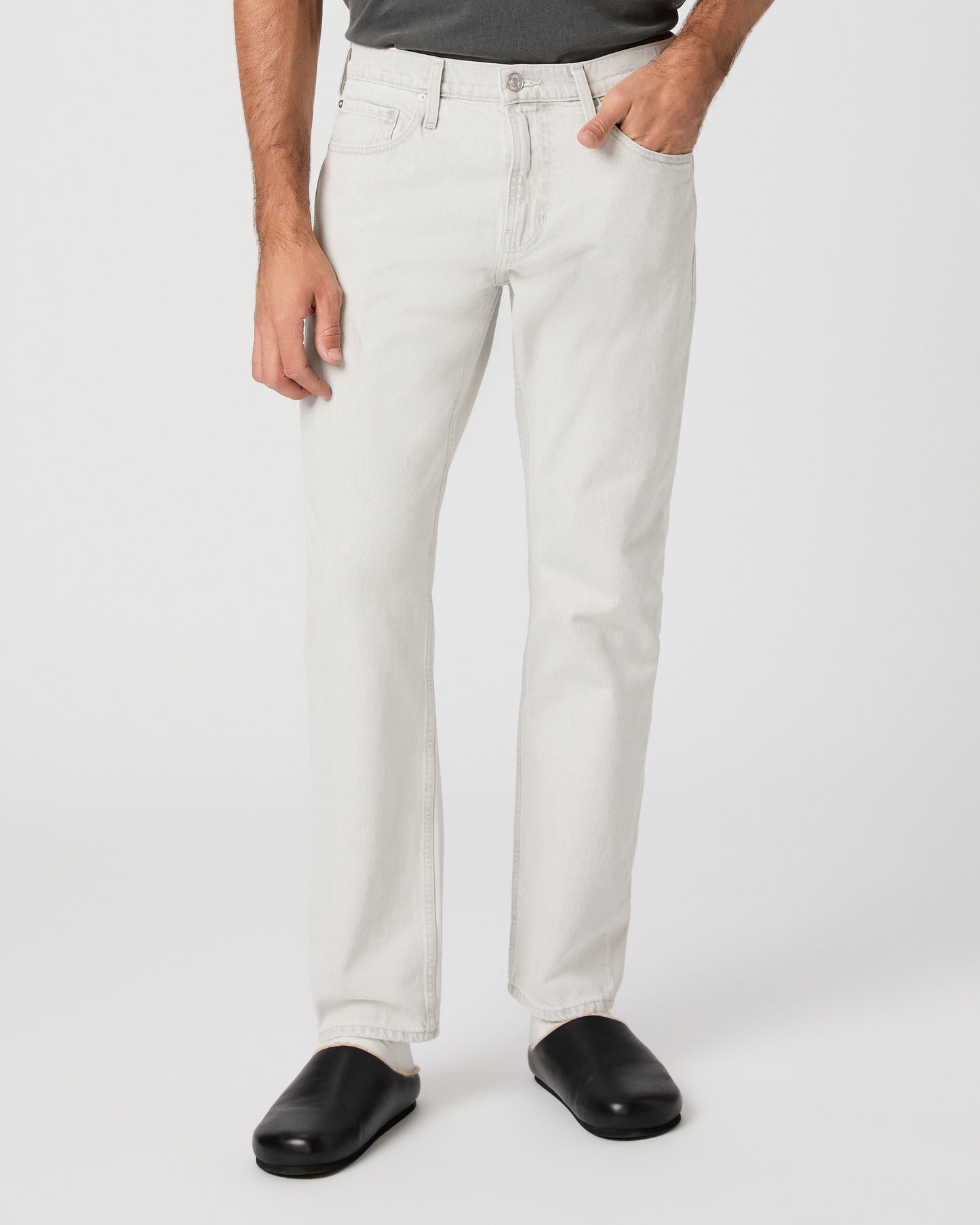 Man wearing a gray t-shirt and white pants on a white background