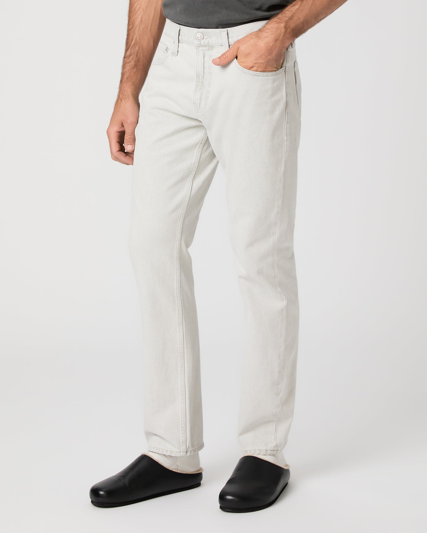 Man wearing a gray t-shirt and white pants on a white background
