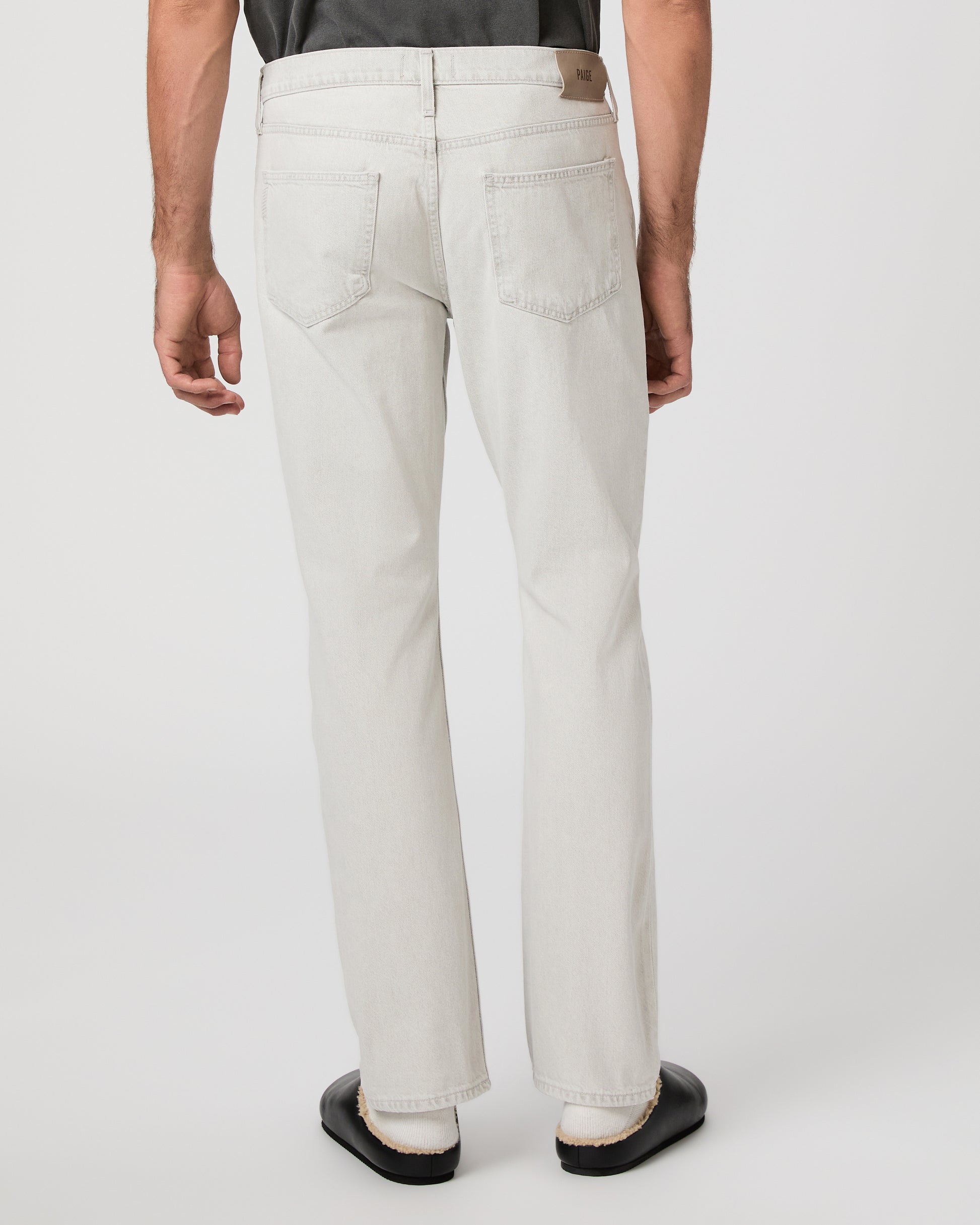 Man wearing a gray t-shirt and white pants on a white background