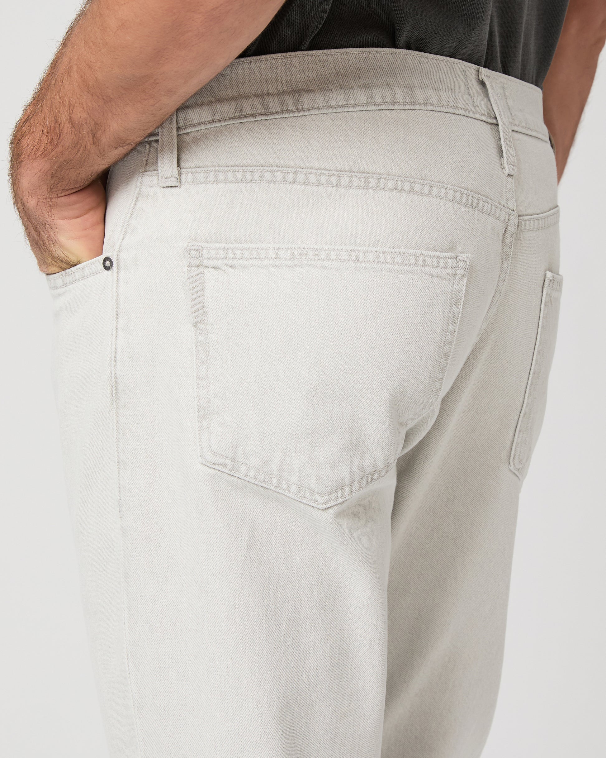 Man wearing a gray t-shirt and white pants on a white background