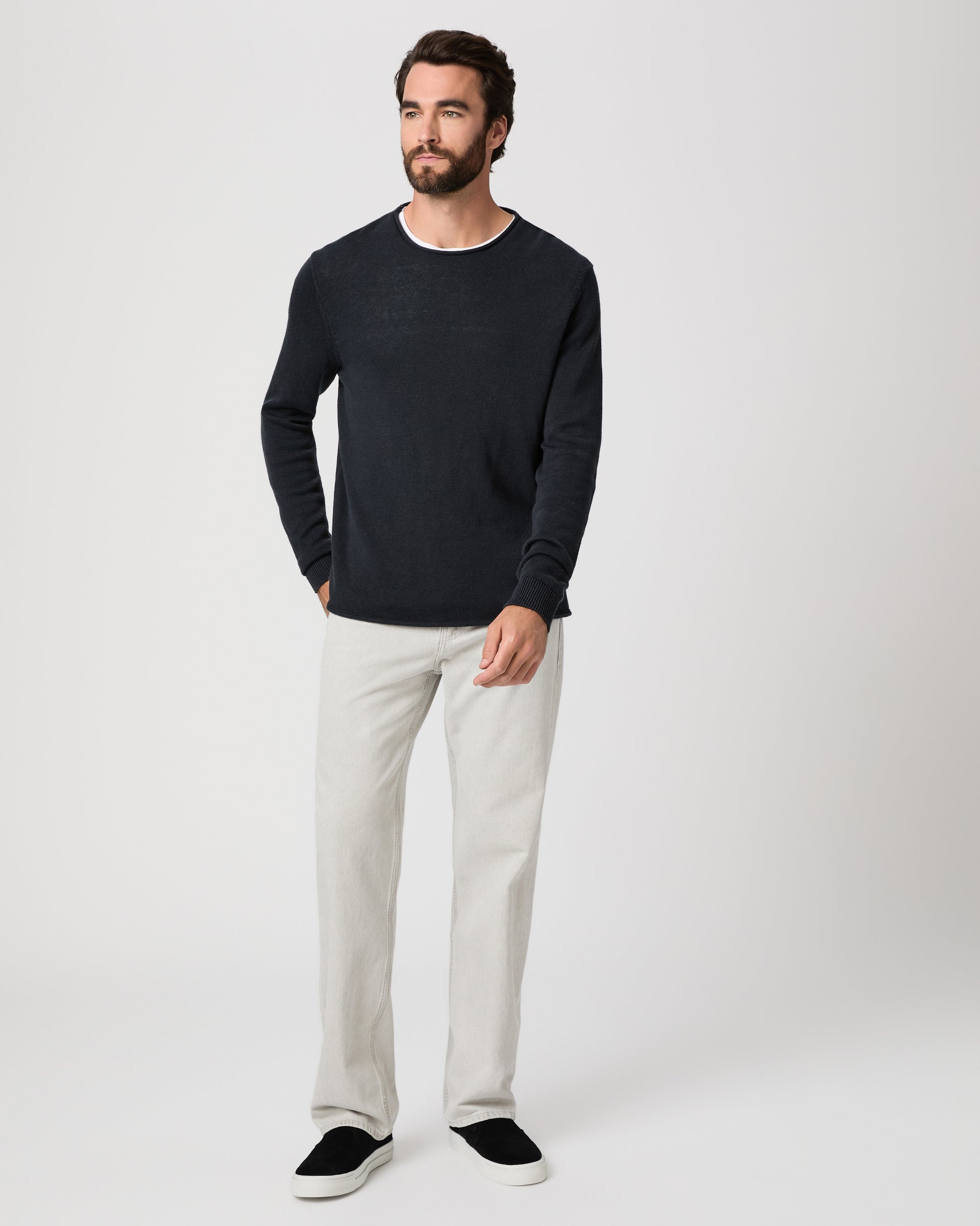 Man wearing a black sweater and grey pants paired with black sneakers on a white background