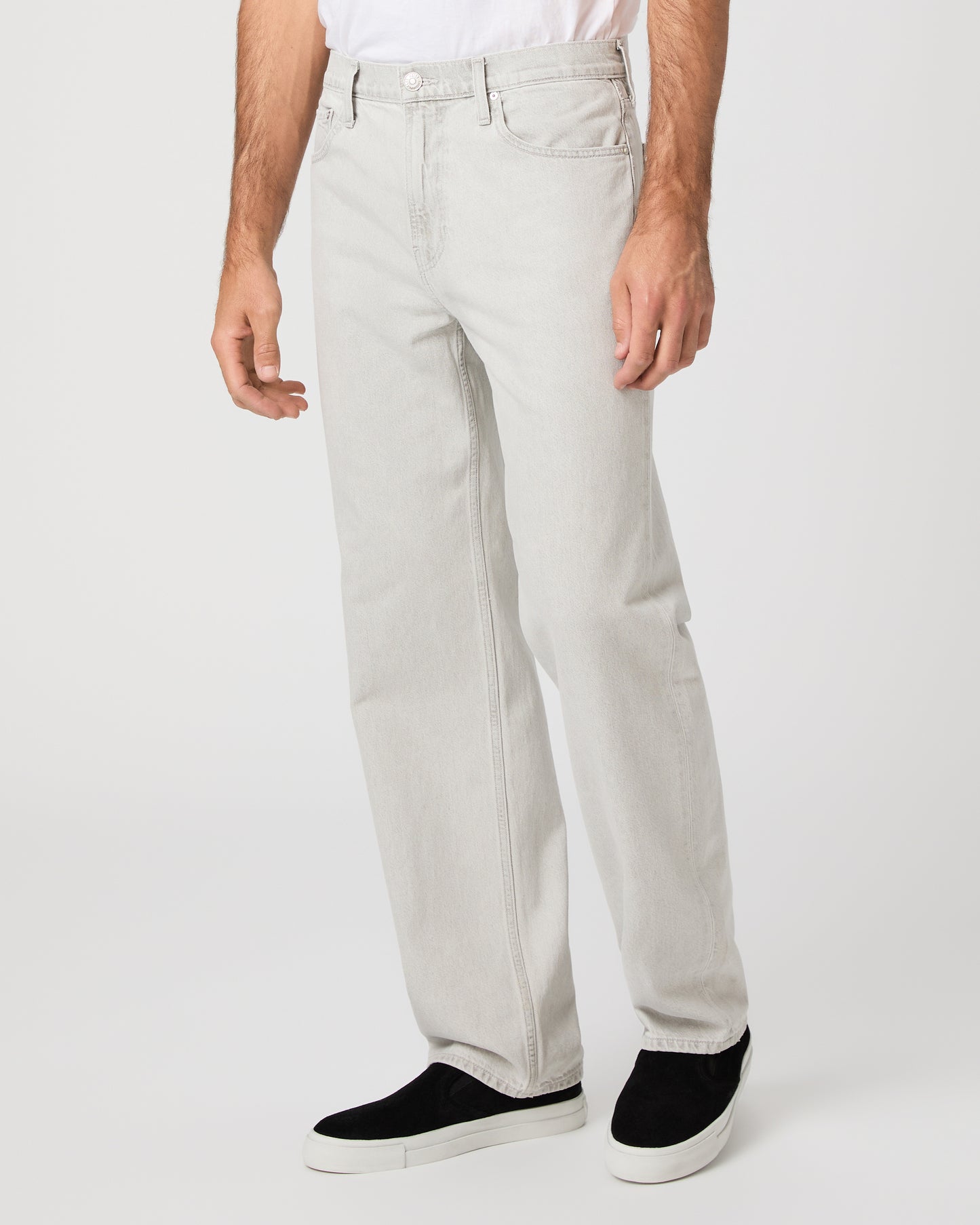 Man wearing a white tee and grey pants paired with black sneakers on a white background