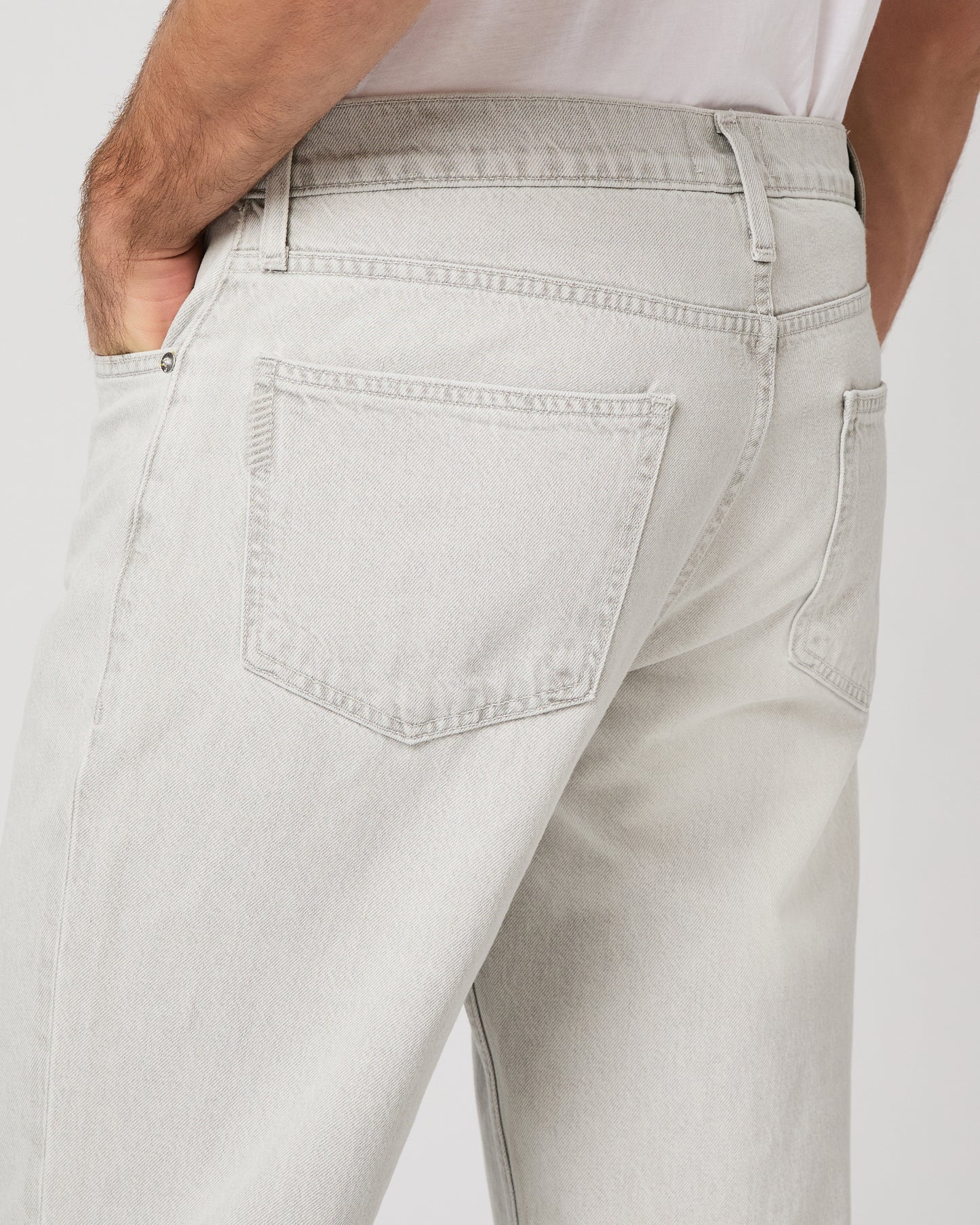Man wearing a white tee and grey pants on a white background