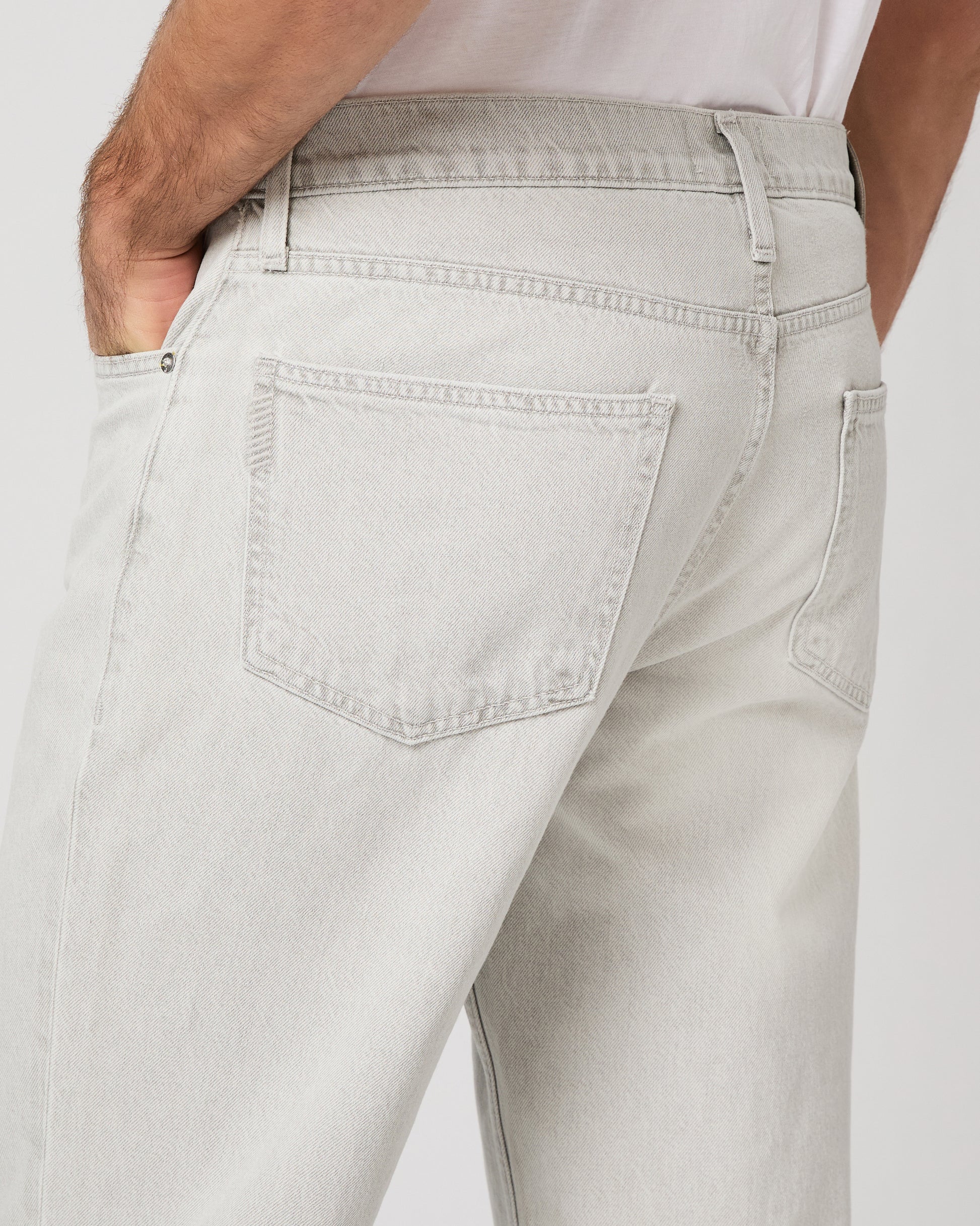 Man wearing a white tee and grey pants on a white background