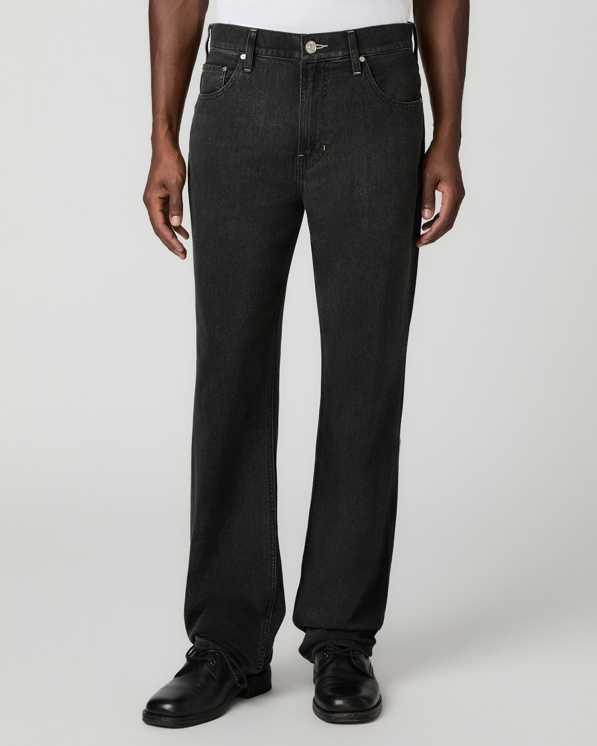 Close front view from the waist down of the charcoal-black relaxed straight jeans, paired with black shoes.