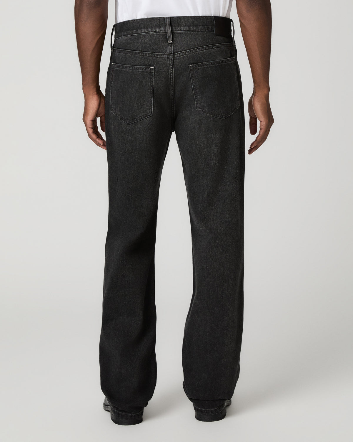 Rear full-length view from the waist down of the charcoal-black relaxed straight jeans, showing the seat and straight leg opening.