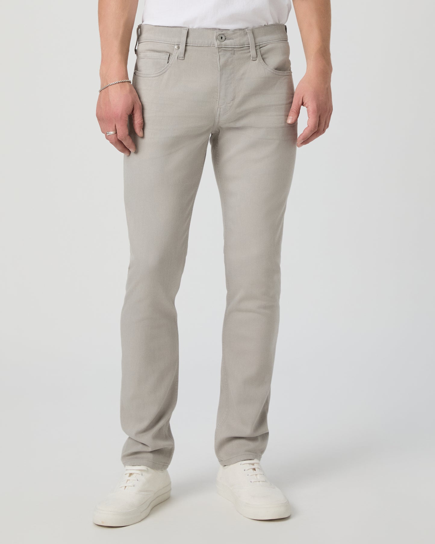Man wearing a white shirt and grey jeans on a light gray background