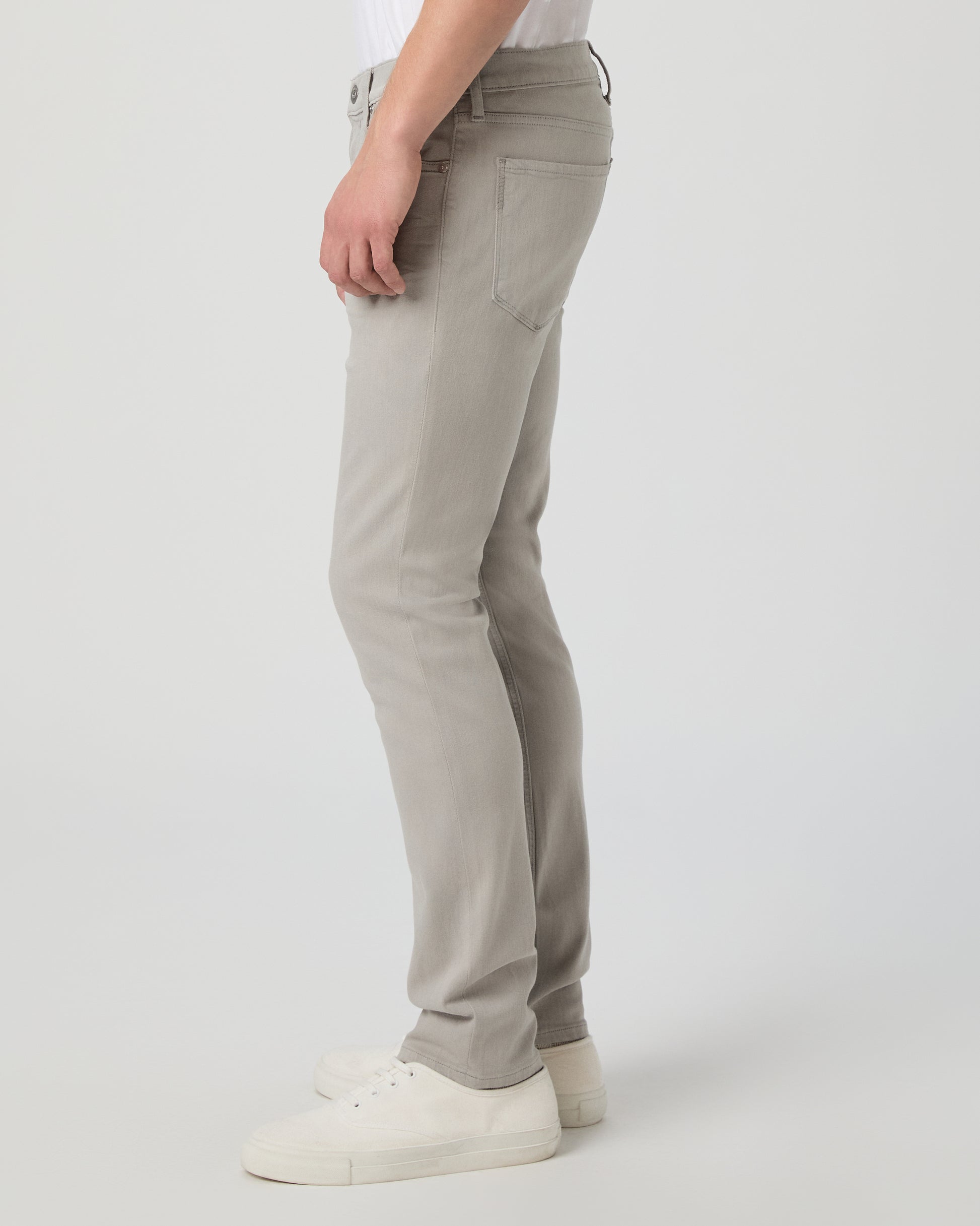 Man wearing a white shirt and grey jeans on a light gray background