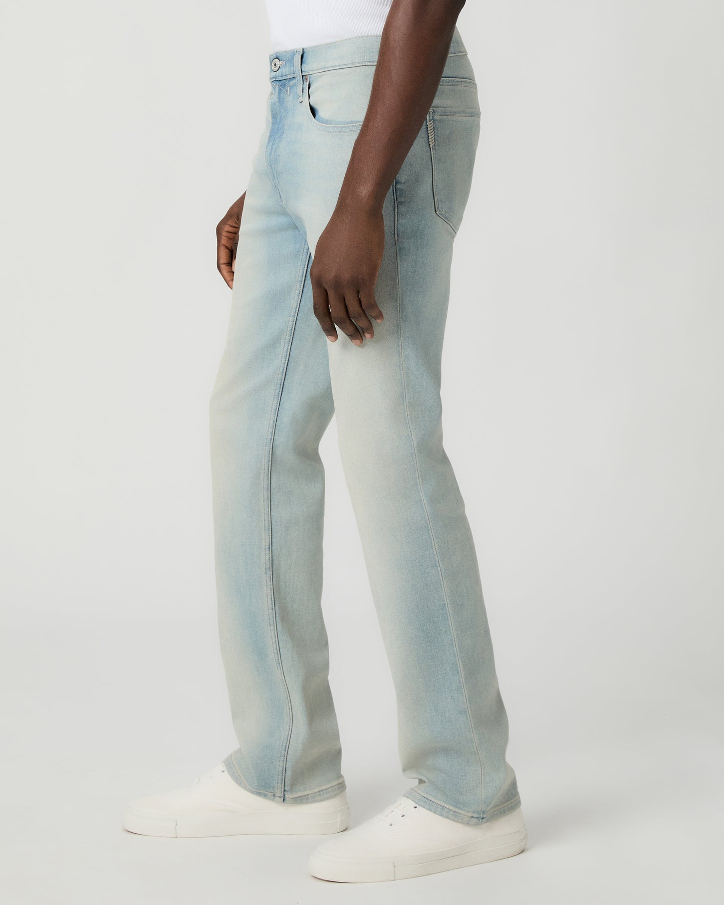 Man wearing a white tee and light blue jeans on a white background