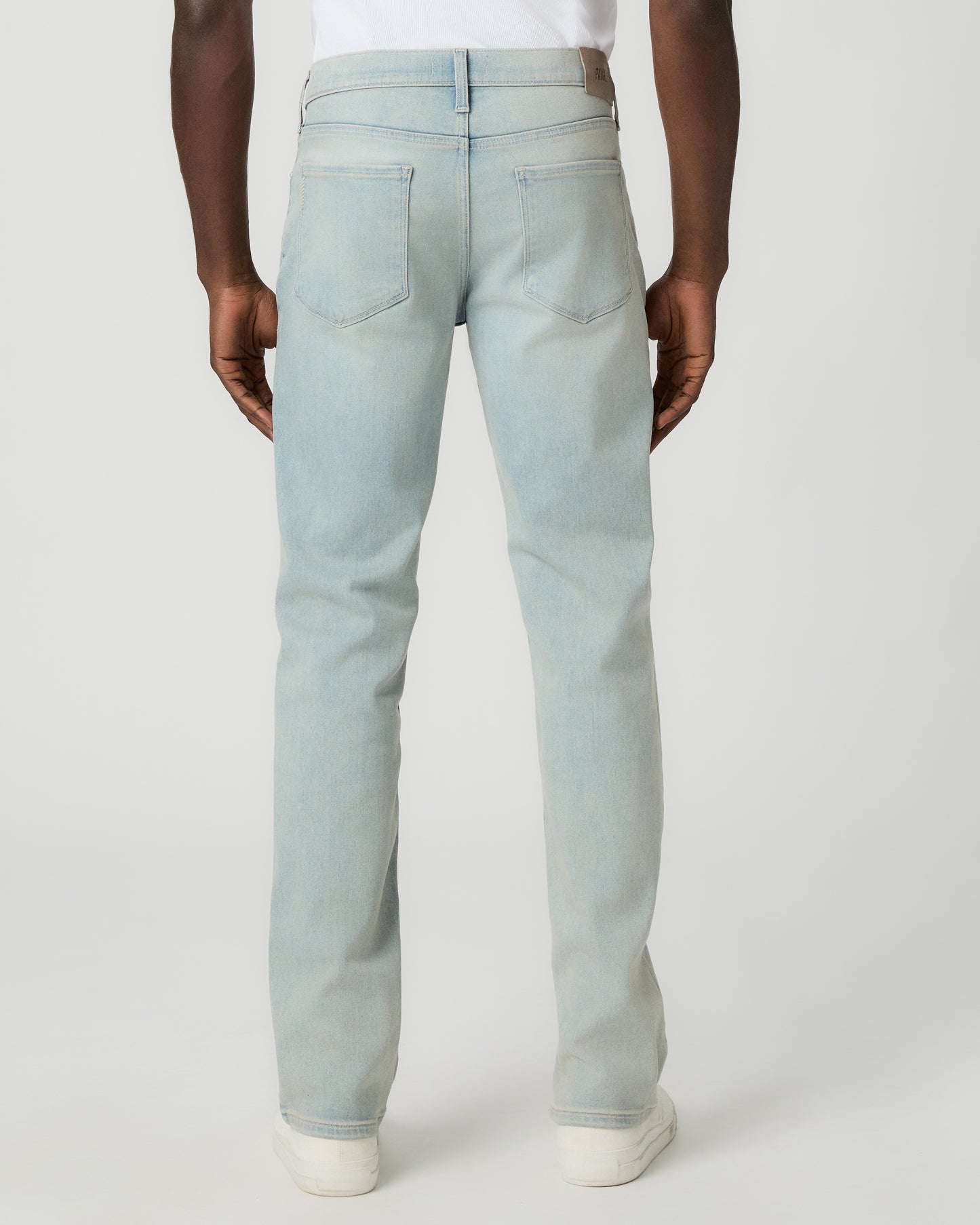 Man wearing a white tee and light blue jeans on a white background