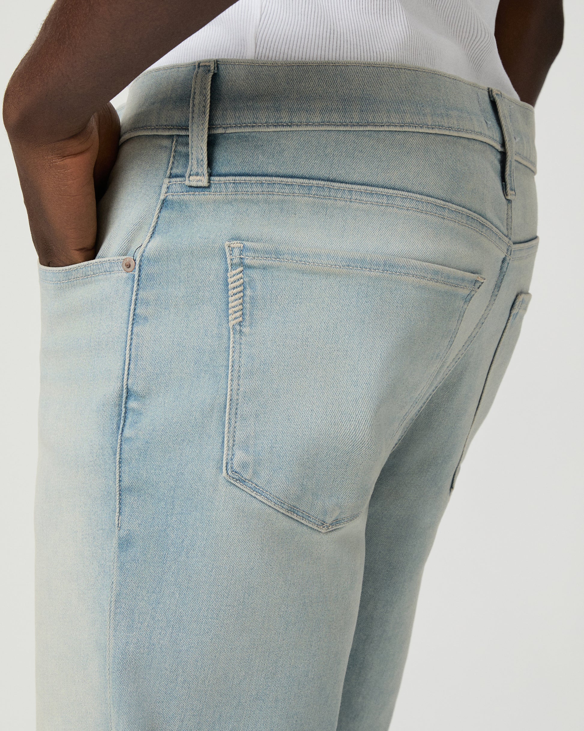 Man wearing a white tee and light blue jeans on a white background
