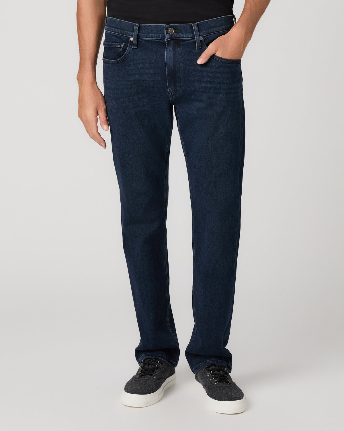 A man modeling a black short-sleeve crewneck t-shirt and dark blue jeans against a light gray studio background.