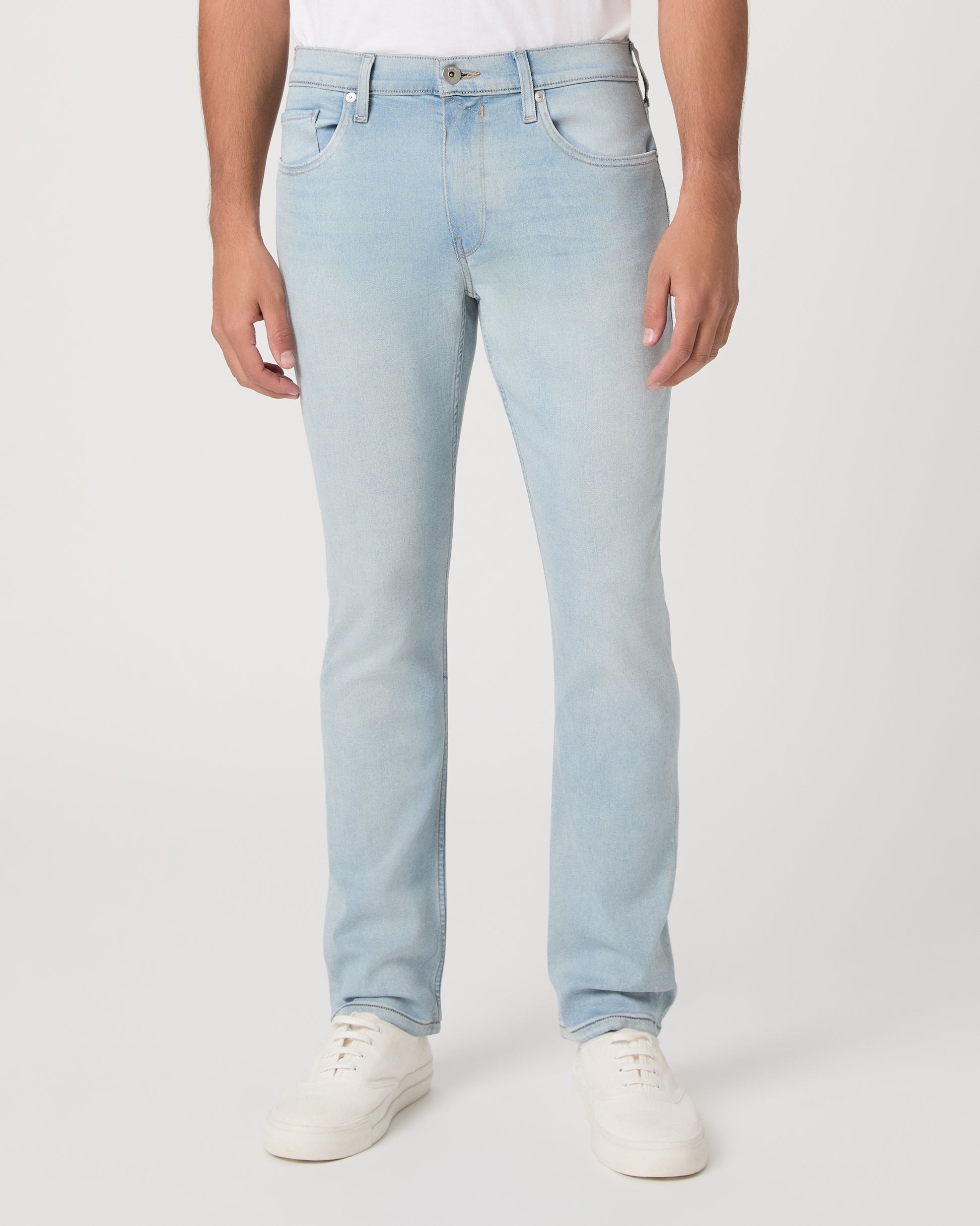 Man wearing a white t-shirt, light blue jeans, and white sneakers on a white background