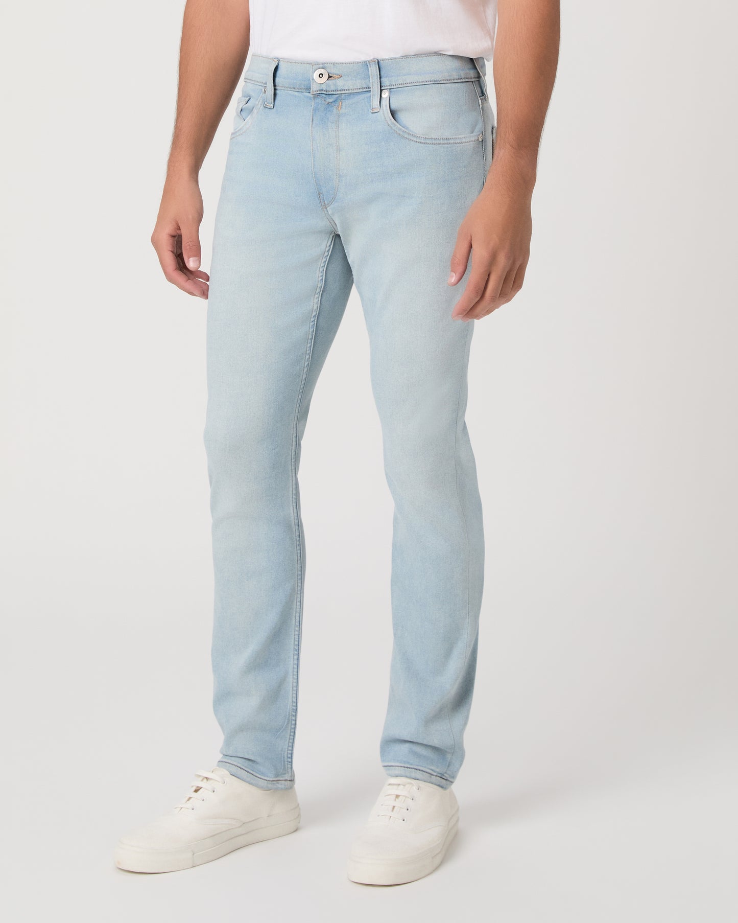 Man wearing a white t-shirt, light blue jeans, and white sneakers on a white background