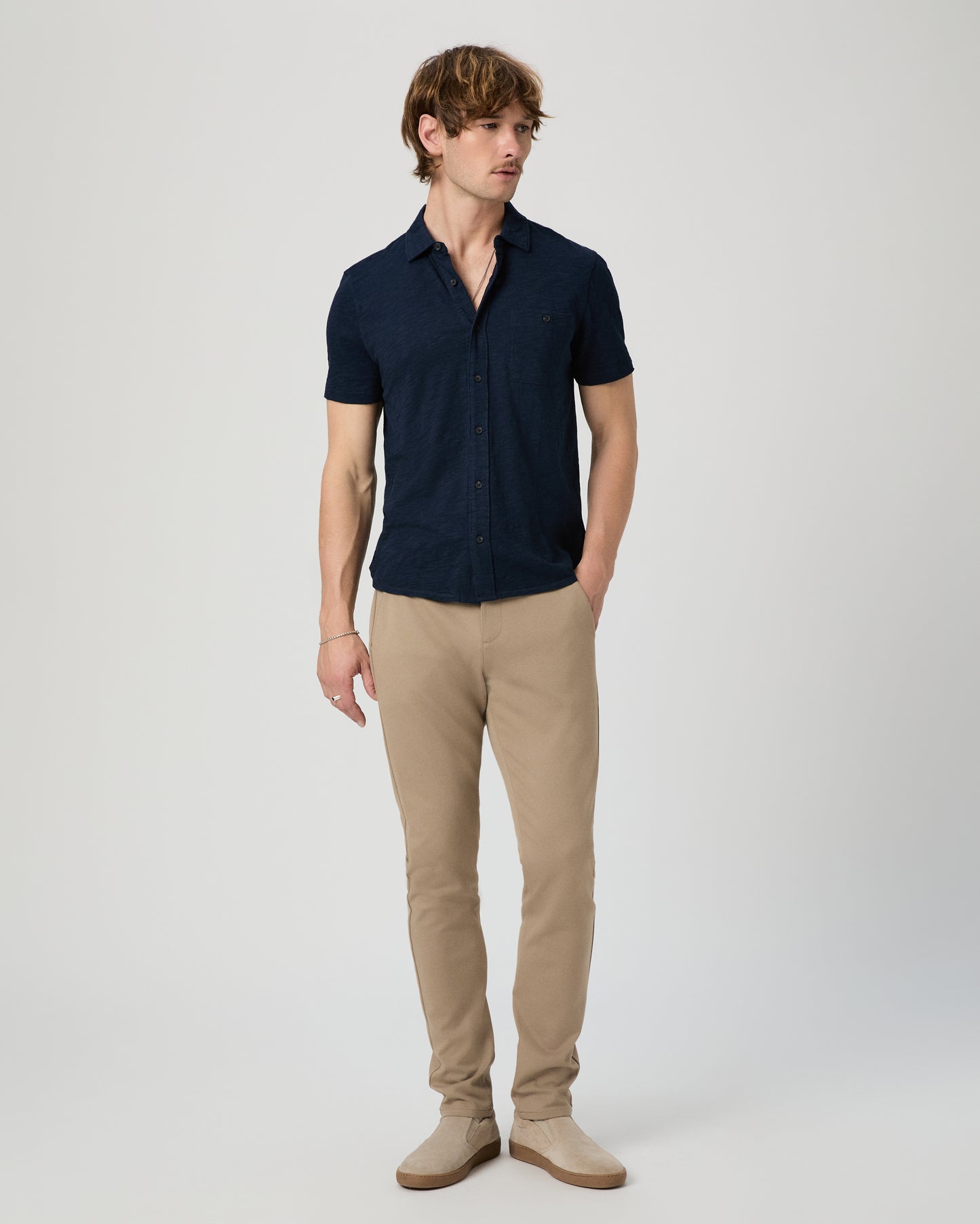 Man wearing a navy shirt and beige pants on a white background