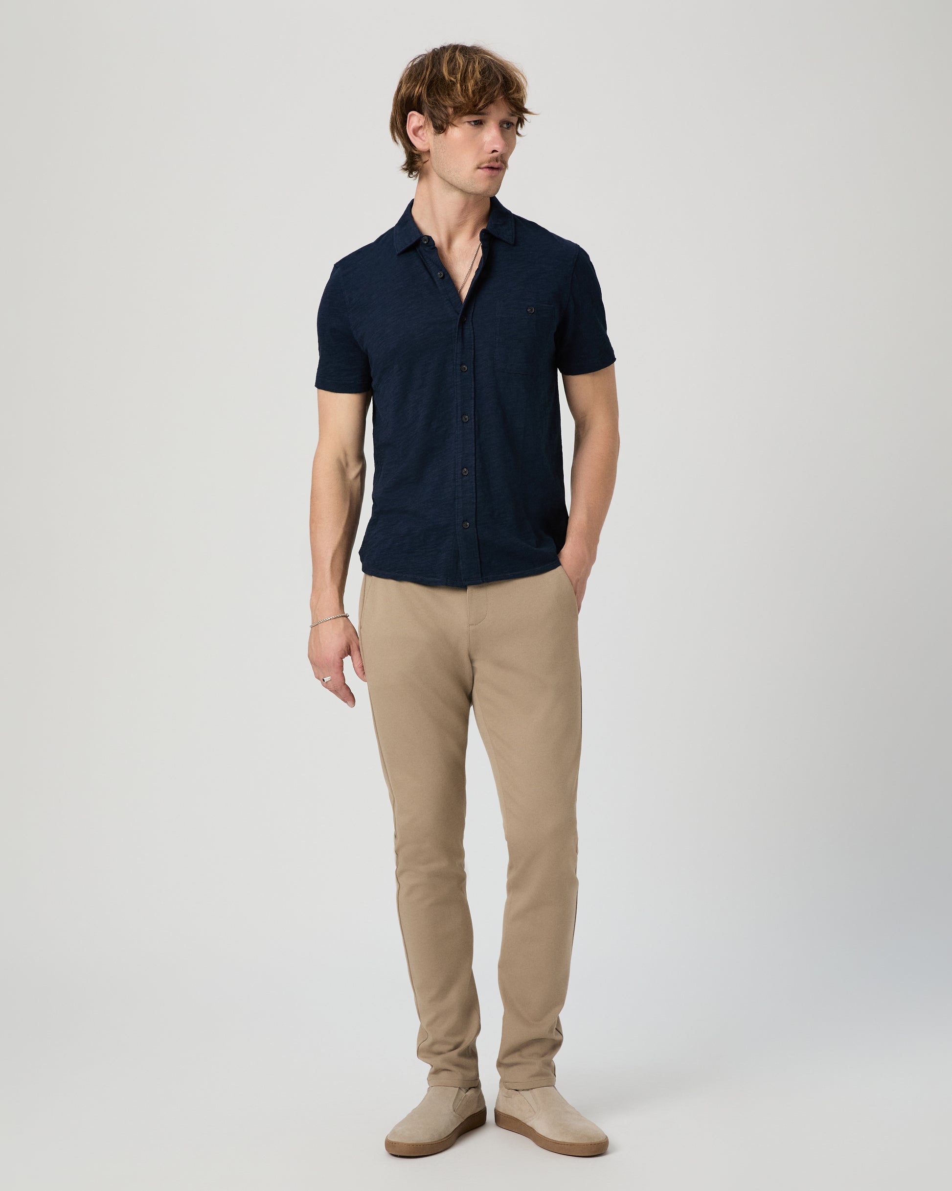 Man wearing a navy shirt and beige pants on a white background