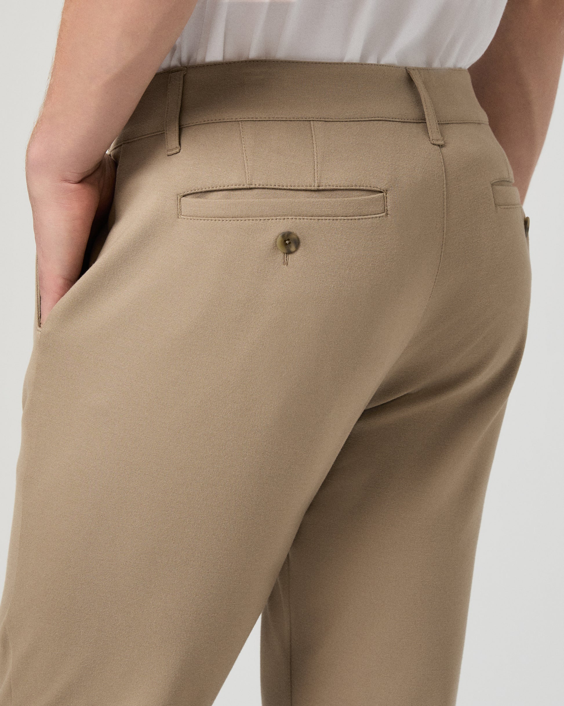Man wearing a white tee and beige pants on a white background