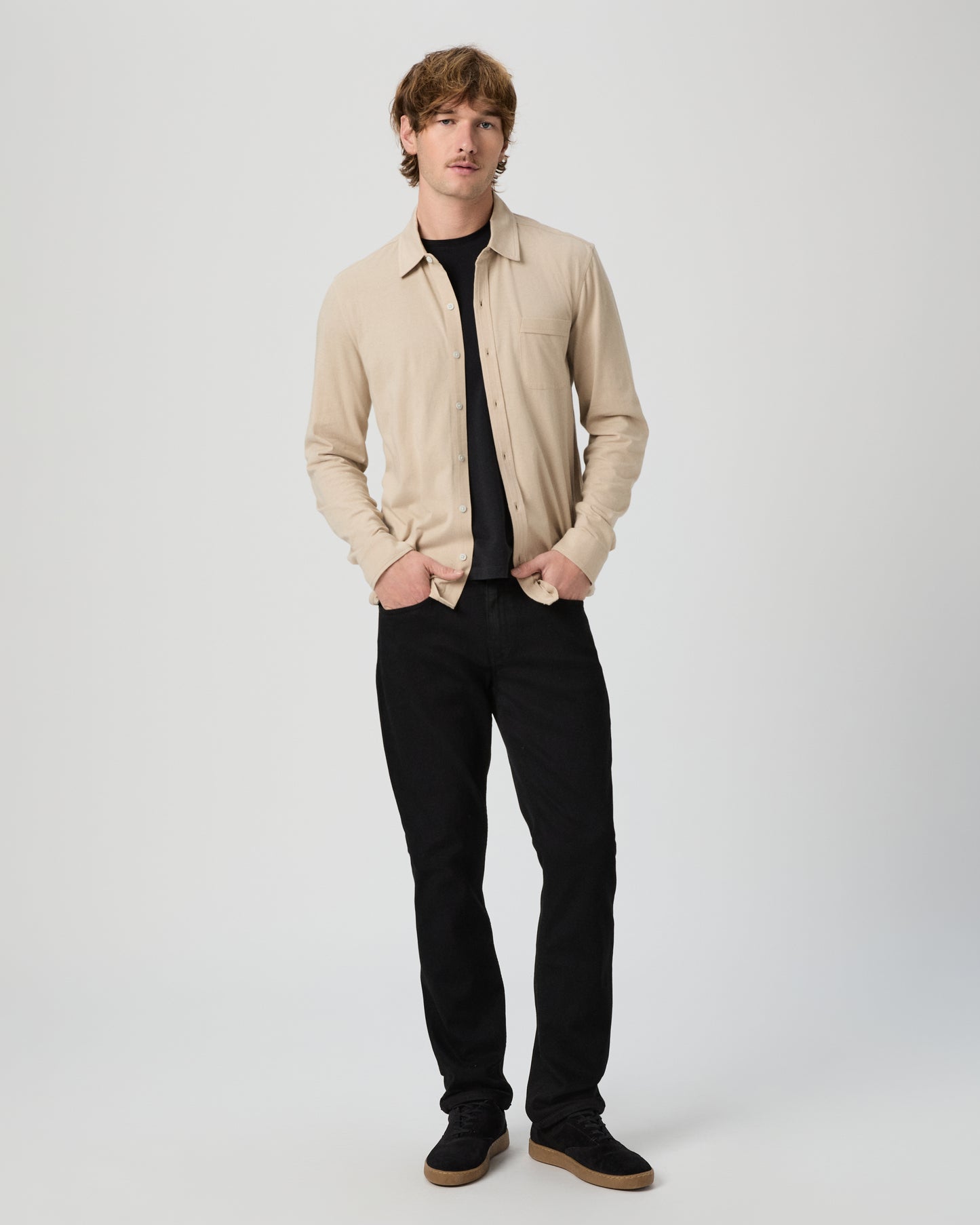 Man wearing a beige shirt and black pants on a white background