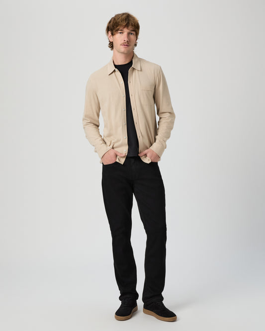 Man wearing a beige shirt and black pants on a white background