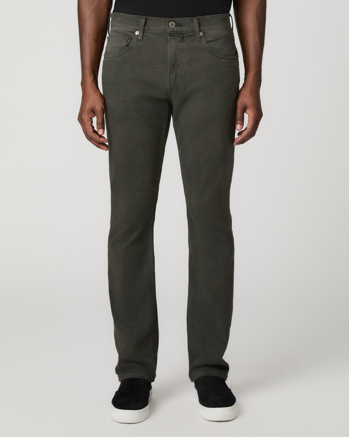 Close front view from the waist down of the greenish-black slim straight jeans, paired with black leather shoes.