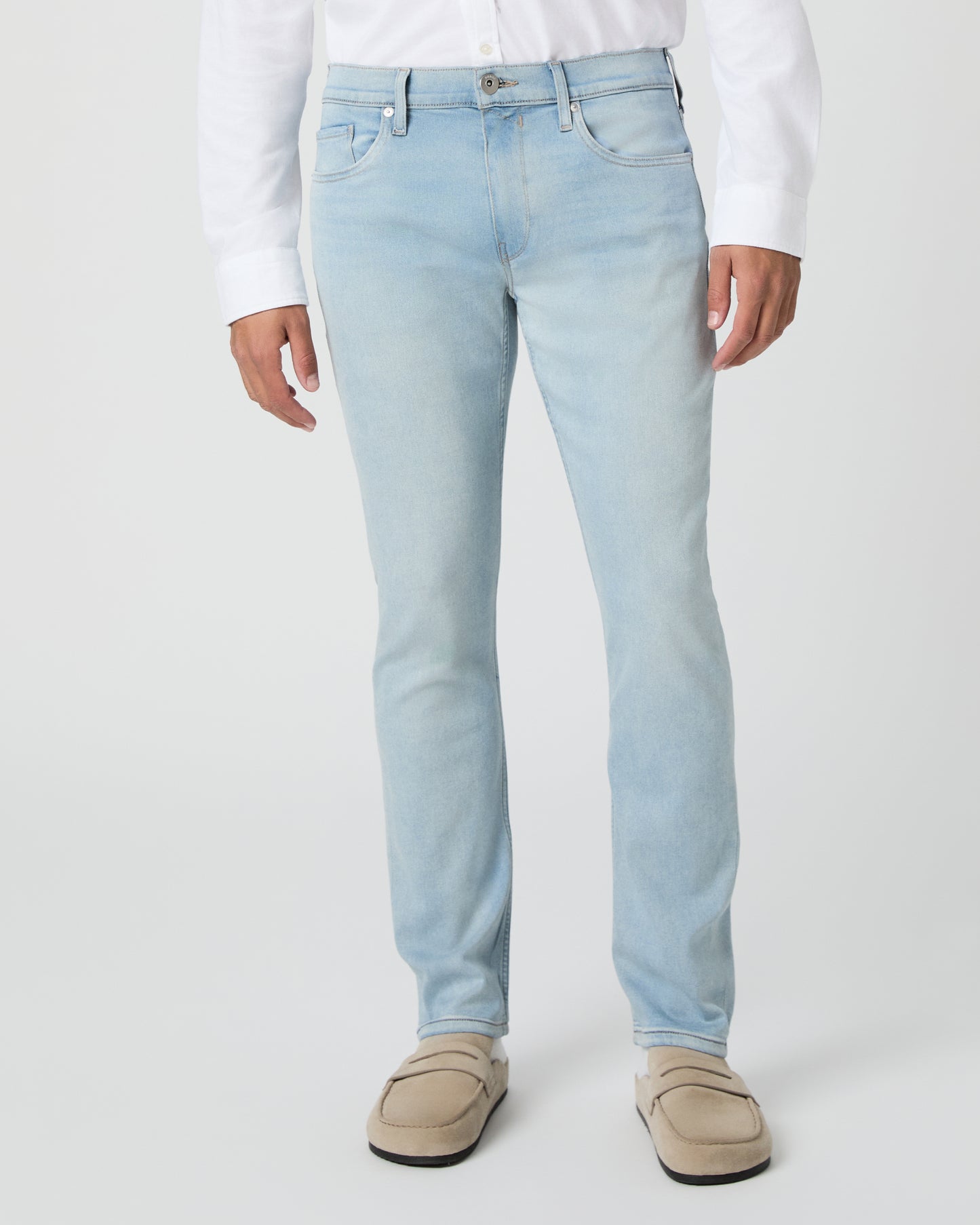 Man wearing a white shirt and light blue jeans against a white background