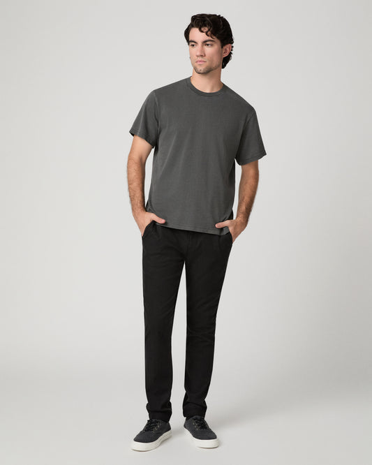 Man wearing grey shirt and black pants against a white background