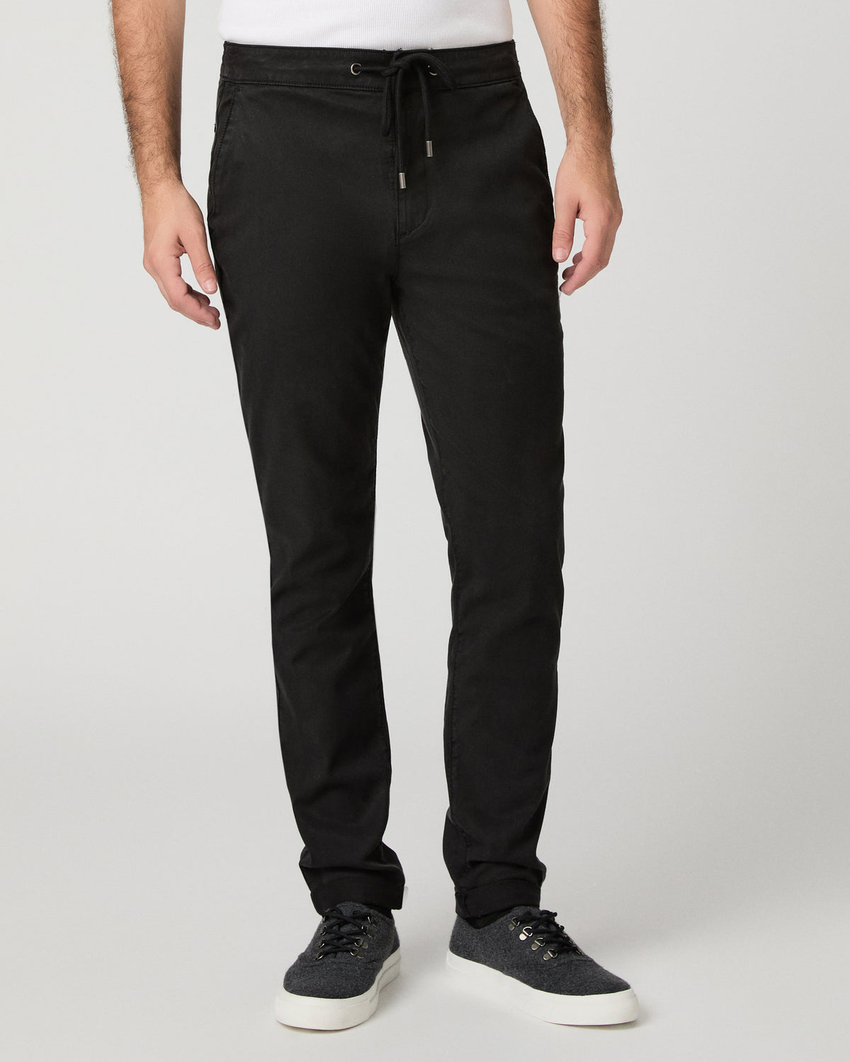 Man wearing grey shirt and black pants against a white background