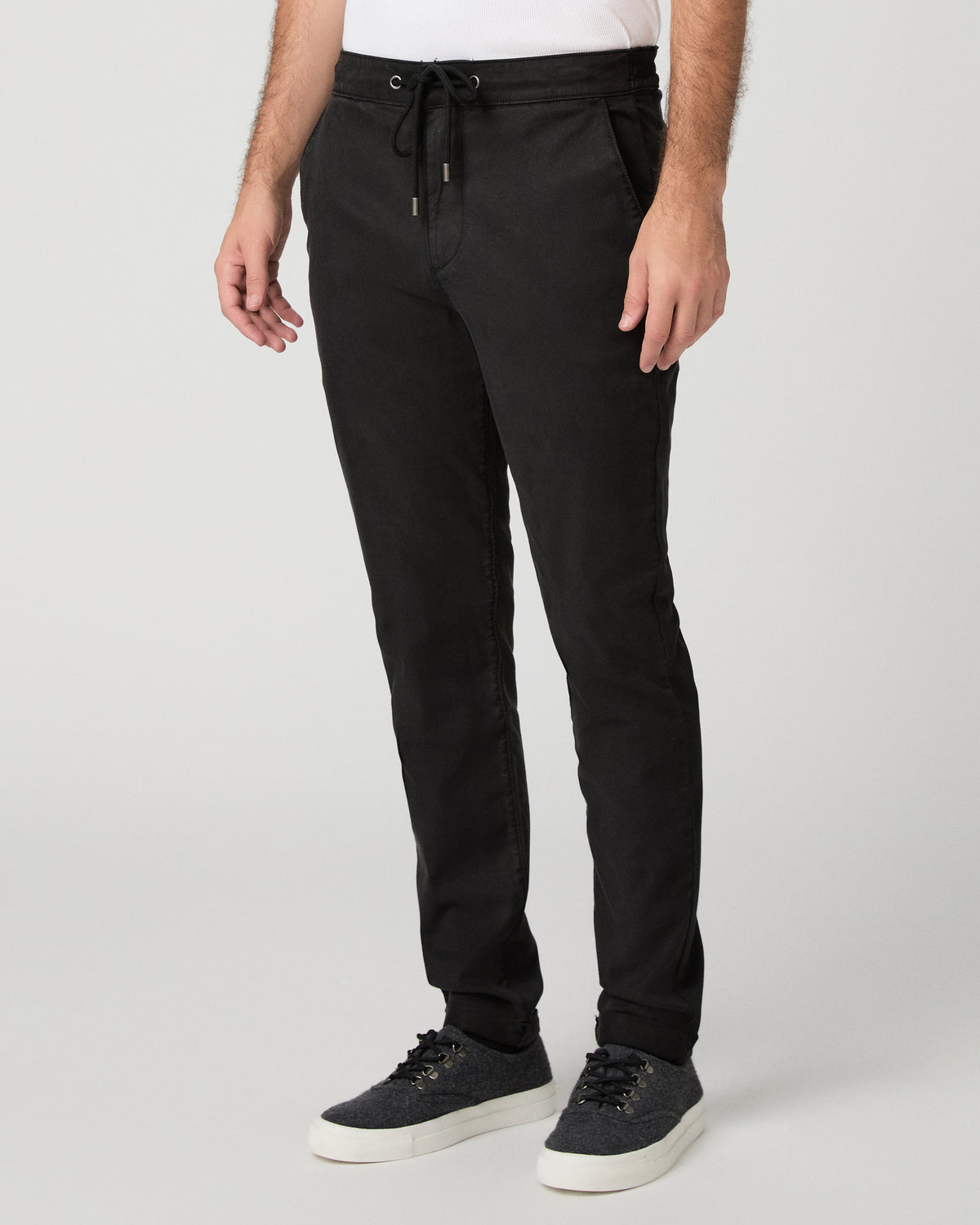 Man wearing grey shirt and black pants against a white background