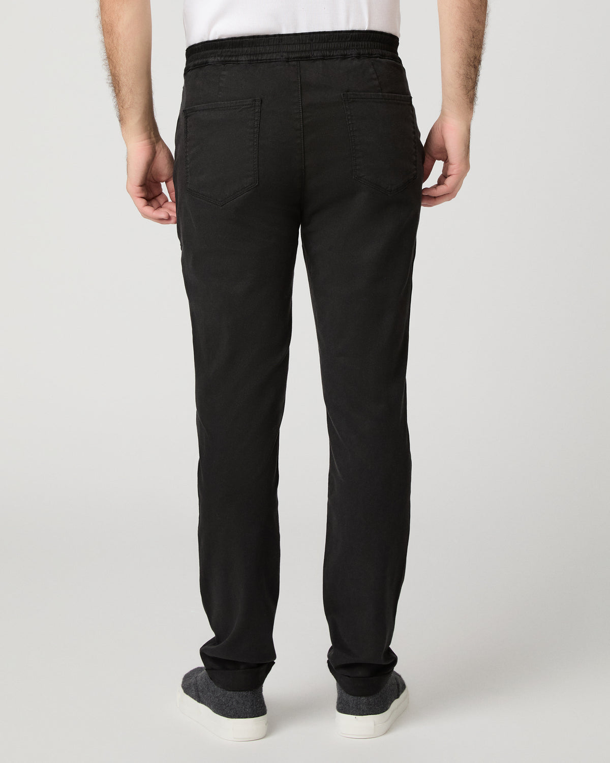 Man wearing grey shirt and black pants against a white background