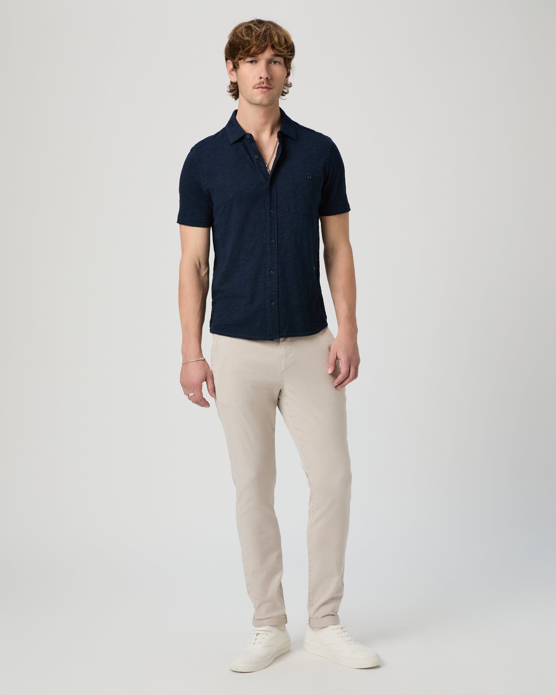 Man wearing a navy polo shirt and beige pants on a white background