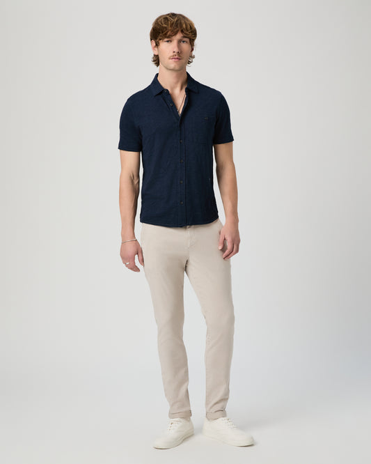 Man wearing a navy polo shirt and beige pants on a white background