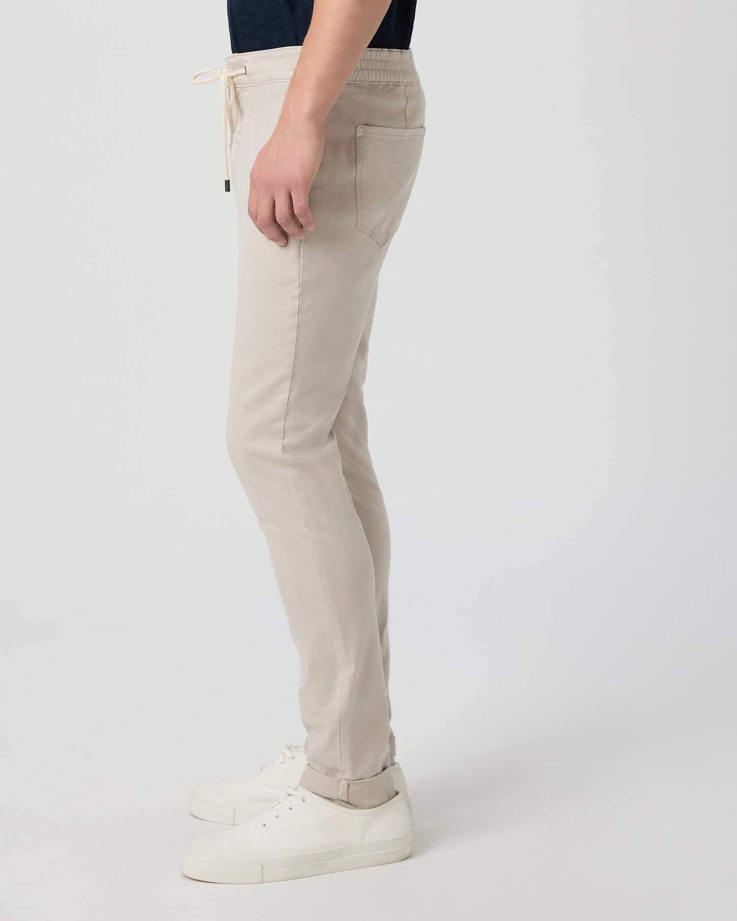 Beige pants worn by a person on a white background