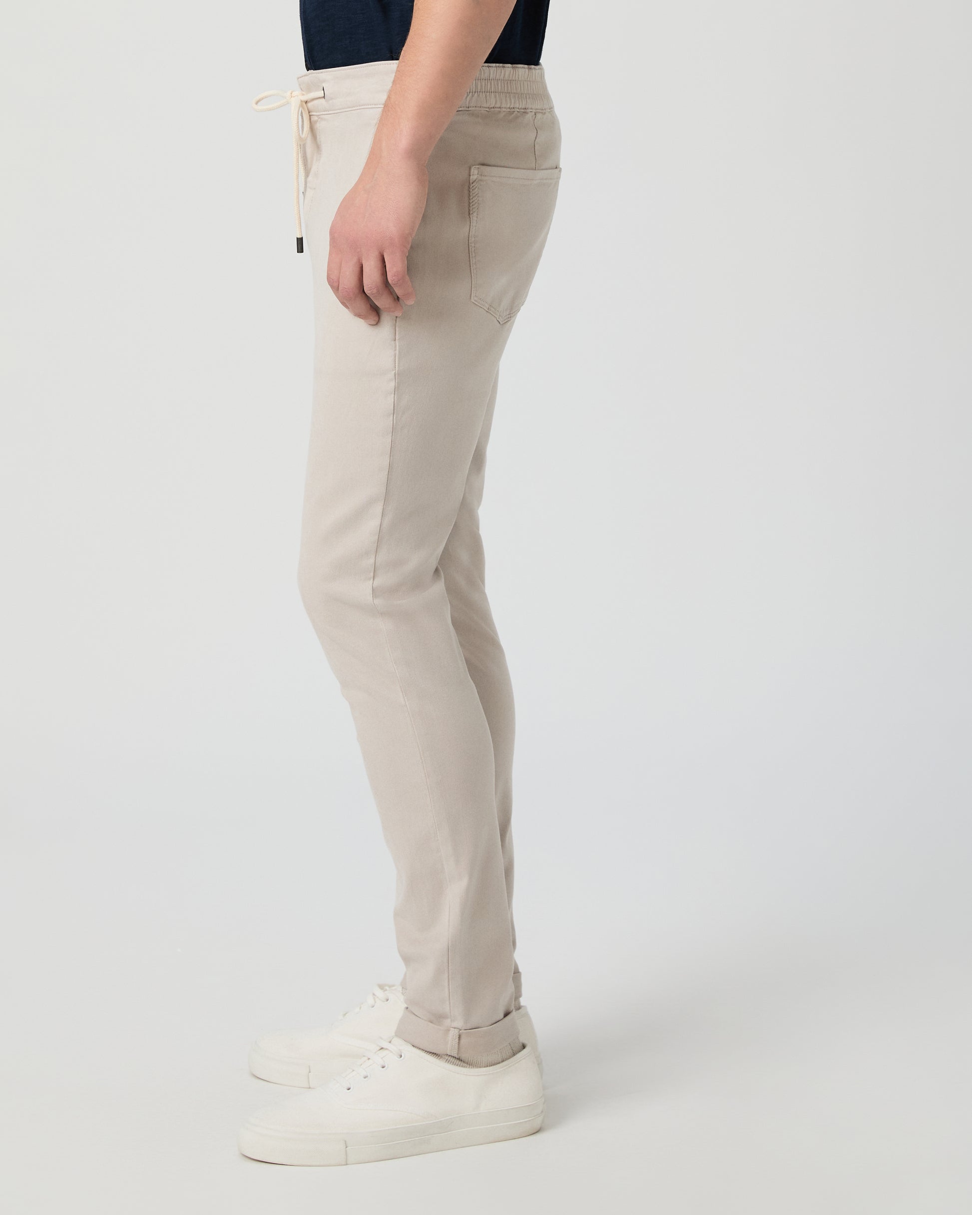 Beige pants worn by a person on a white background