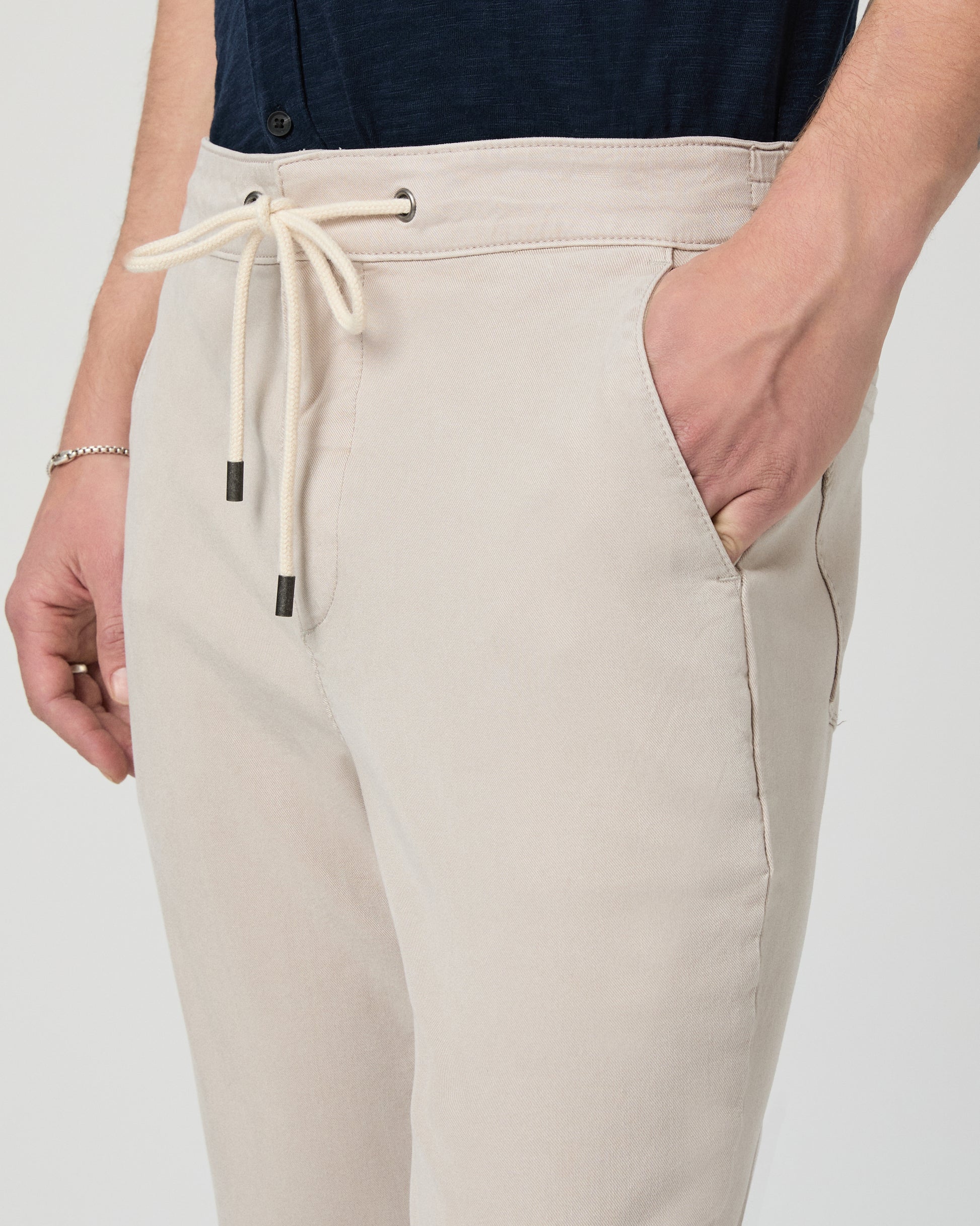 Beige jogger pants with a drawstring on a plain background