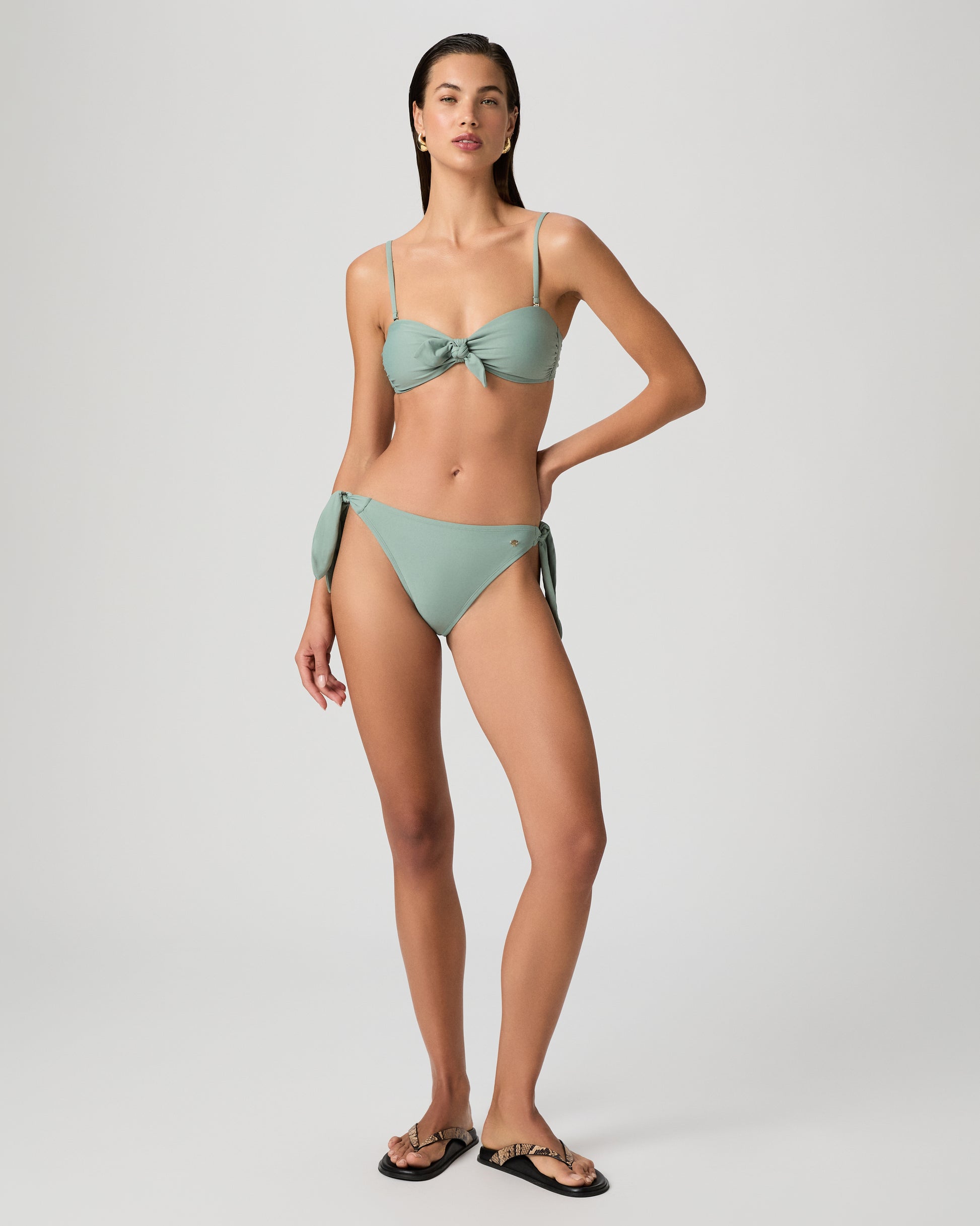 Woman wearing a light green bikini set on a white background