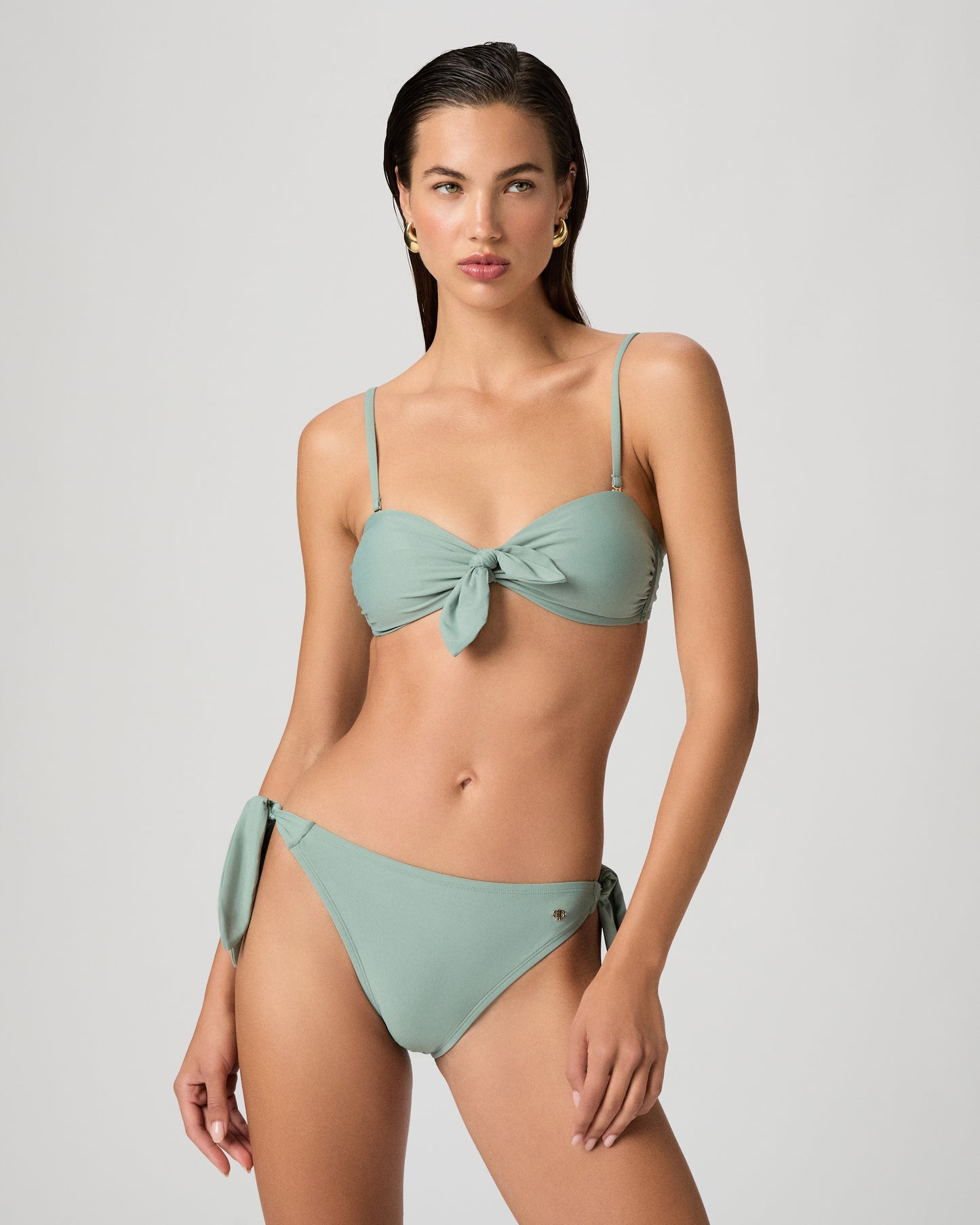 Woman wearing a light green bikini set on a white background